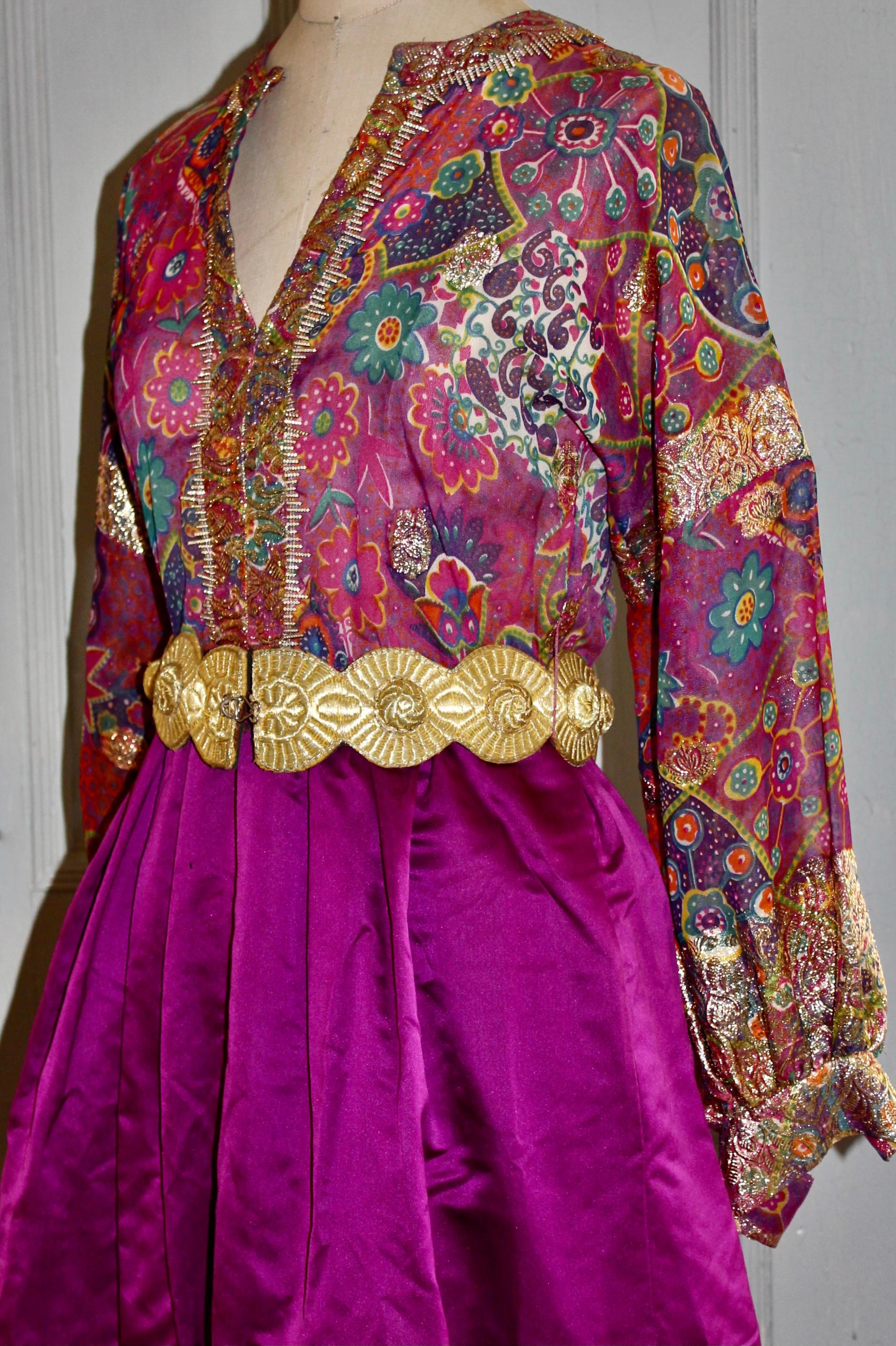 An Indian inspired gown with a colorful metallic semi shear silk organza top, and a violet
floor length silk taffeta skirt. Belted with a gold leather clasped belt. 28