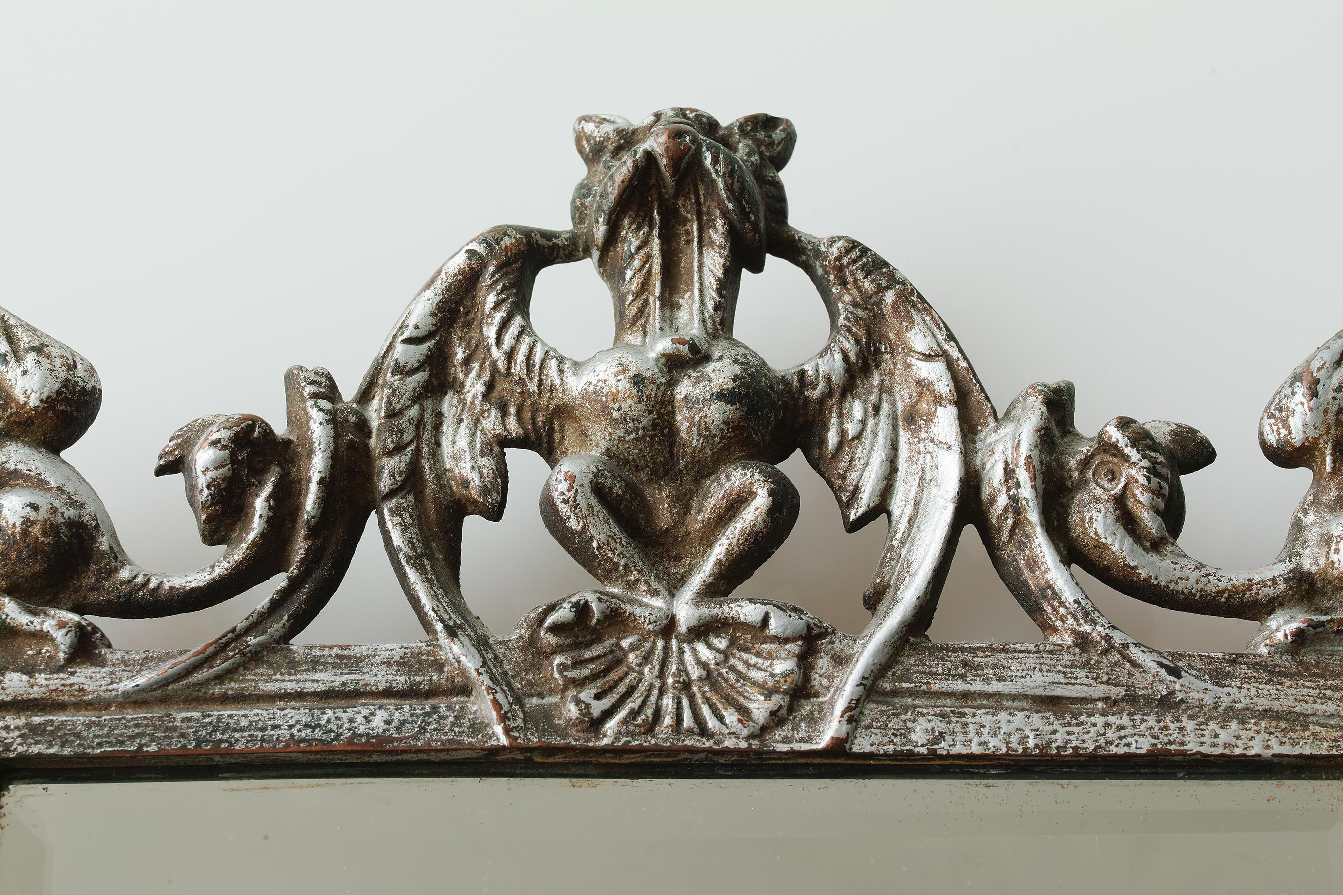 For your consideration is this circa 1920s cast metal mirror in the style of Oscar Bach. The top has a griffin perched atop a seashell which is flanked on either side by a dragon whose tail coils down cattail plants that flank the sides of the