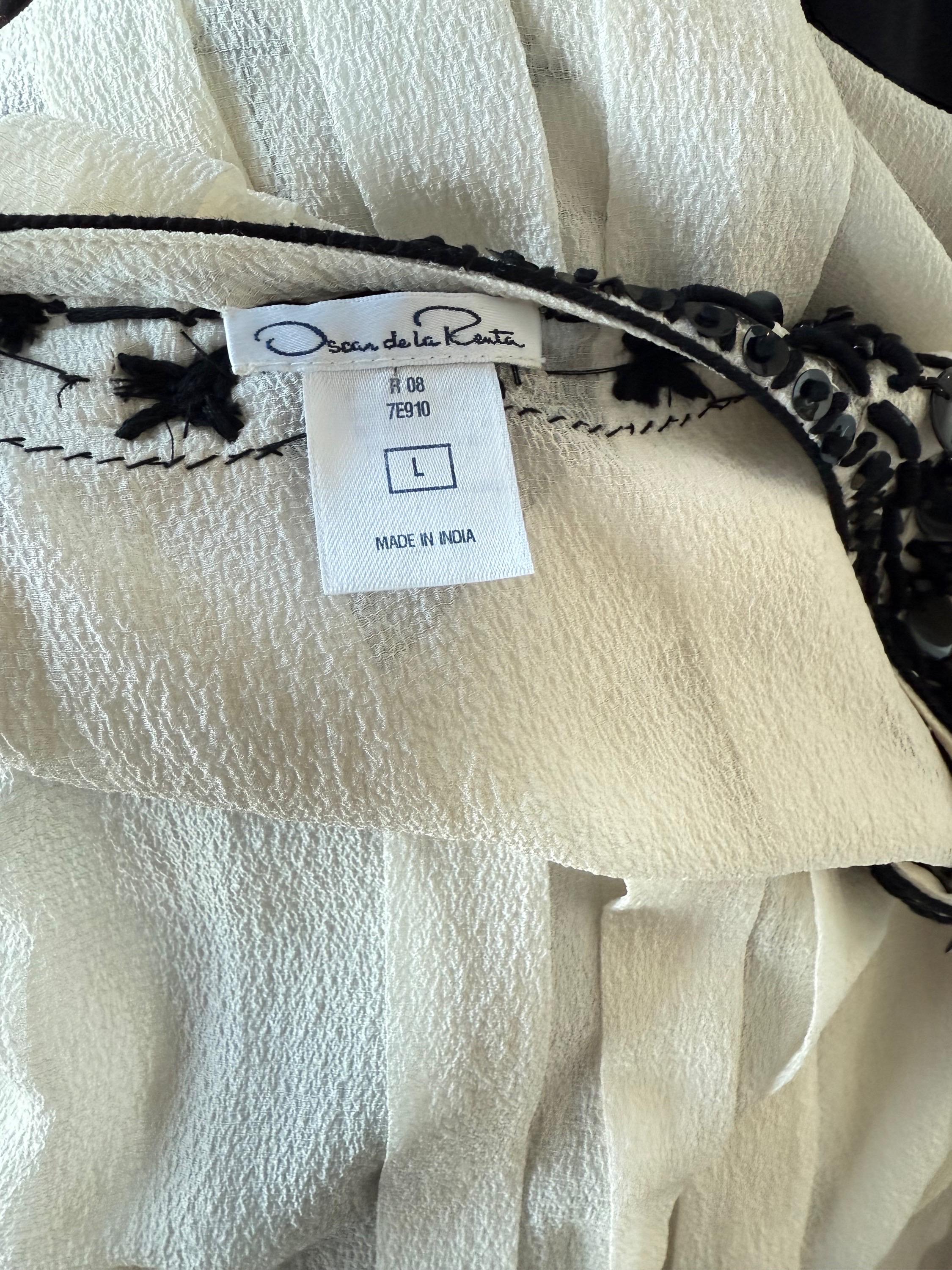 Beautiful vintage ( Y2K ) Oscar de la Renta white silk tunic shirt with black sequins and beads ! Features thousands of hand-sewn sequins and beads in various shapes at chest, neck and sleeve cuffs. Hook-and-eye closure at top center neck. Super