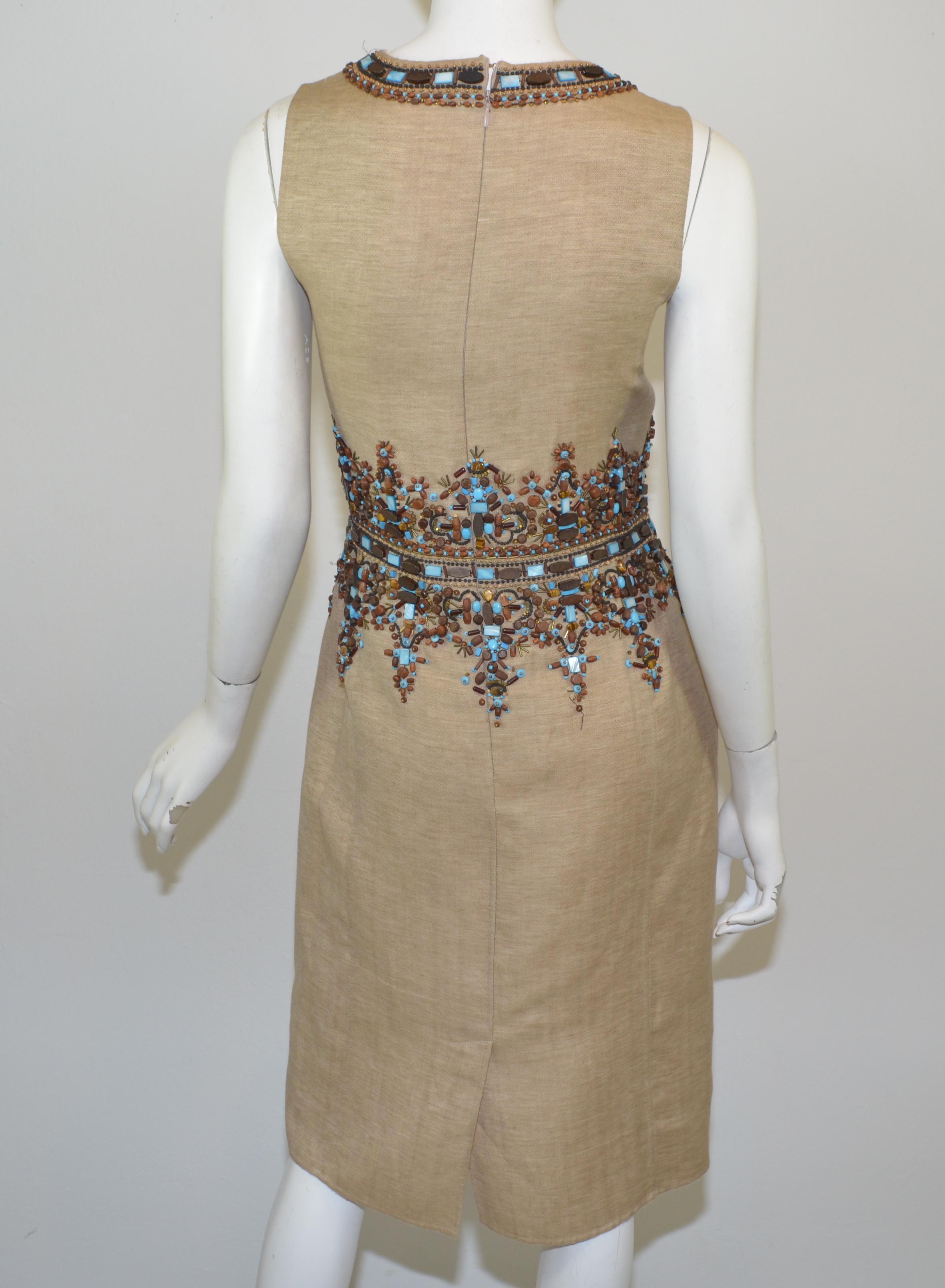 Das Kleid von Oscar de la Renta ist aus einer Leinenmischung gefertigt und hat eine schöne Perlenverzierung am Ausschnitt und an der Taille. Das Kleid hat einen Reißverschluss am Rücken und einen Haken- und Ösenverschluss.