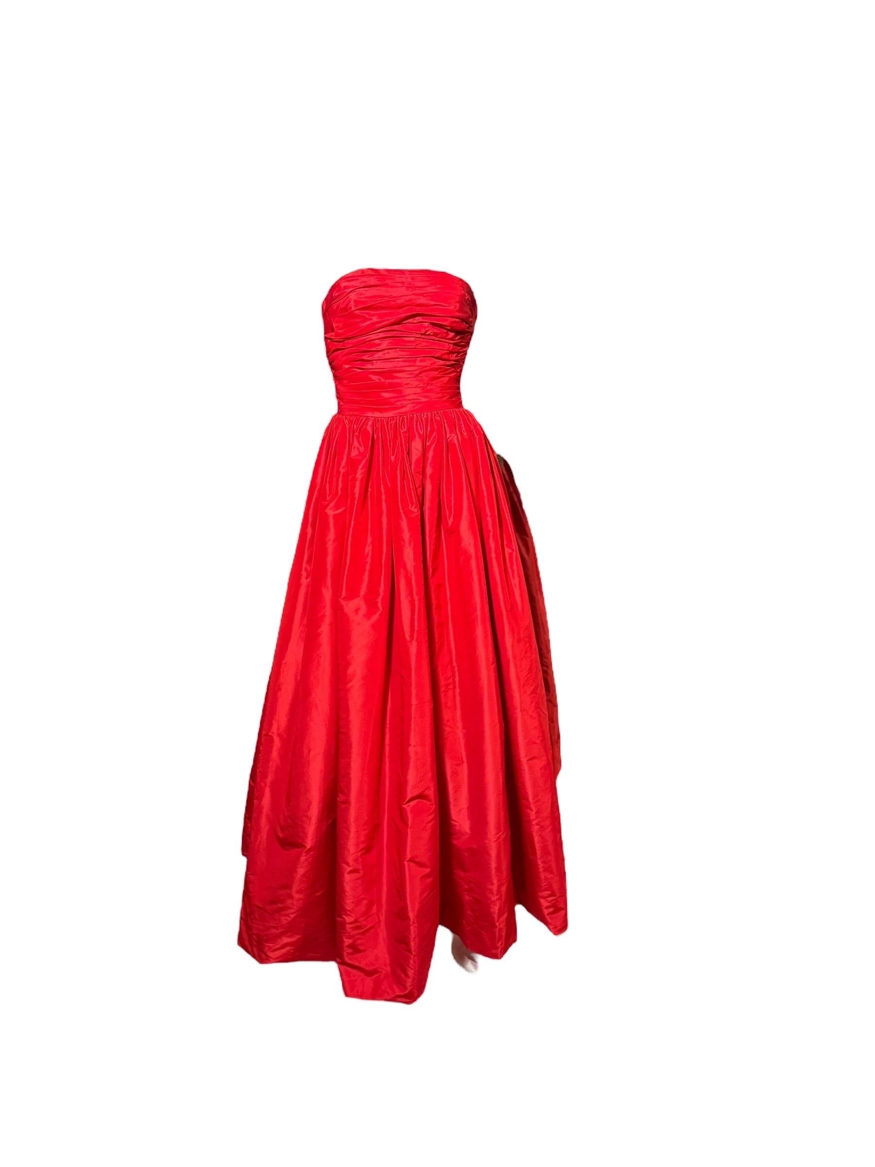 Llama la atención con este vestido de fiesta sin tirantes de alta costura de Oscar De La Renta de la colección 2011, exquisitamente confeccionado en tafetán de seda escarlata vibrante. El corpiño fruncido esculpe la cintura antes de desembocar en