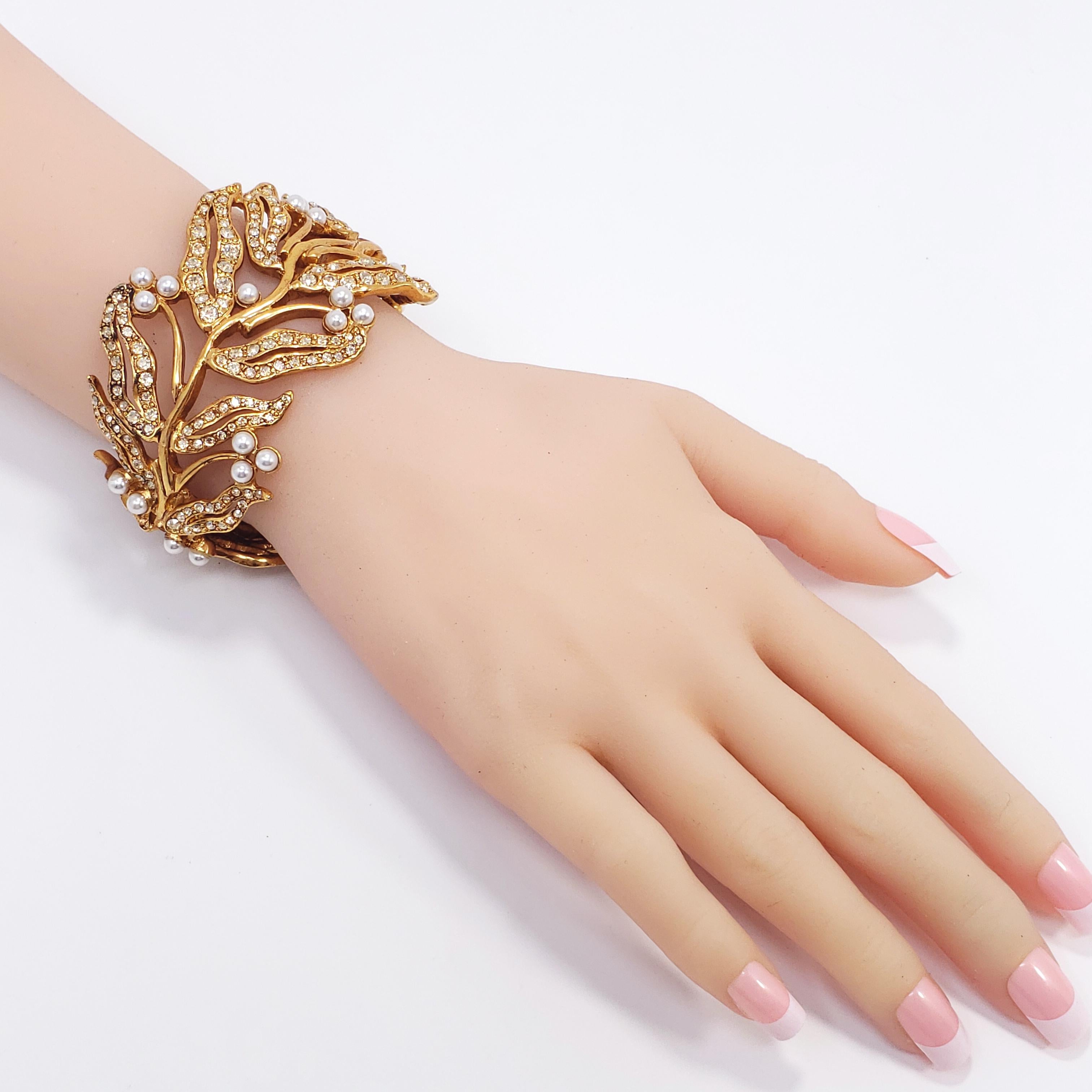An exquisite hinged cuff bracelet by Oscar de la Renta. Features bamboo leaf motifs decorated with brilliant crystals and faux pearls. Hinged, with magnetic closure.

Inner diameter at widest part: 5.9 cm
Inner circumference: 16.75 cm
Height: 4.2 cm