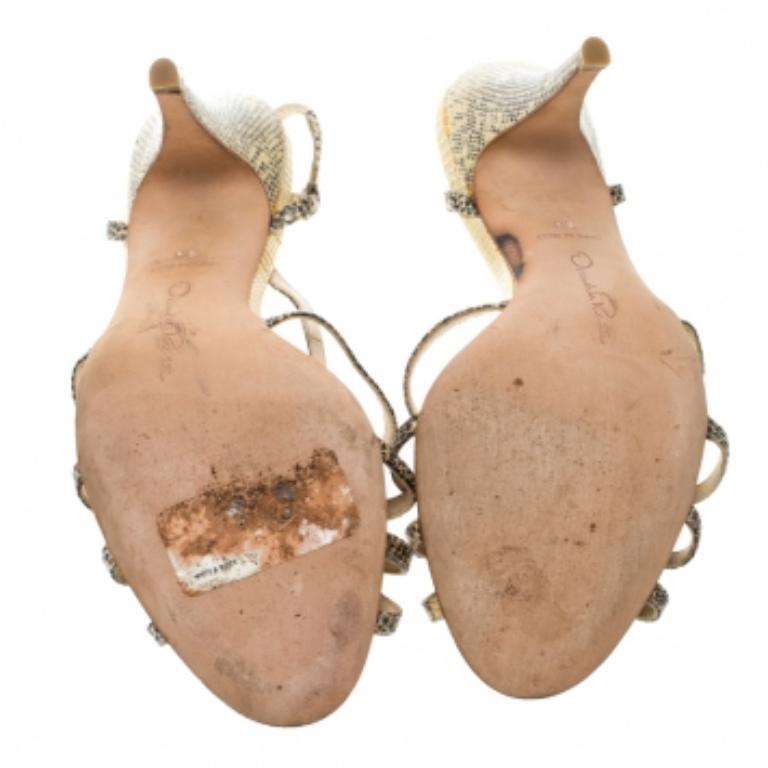 Wie wunderschön sind diese beigen Sandalen von Oscar de la Renta! Diese aus Schlangenleder gefertigten Sandalen haben eine offene Zehensilhouette mit verschlungenen Riemen. Sie sind mit Slingbacks, bequemen Innensohlen und 10 cm hohen Absätzen