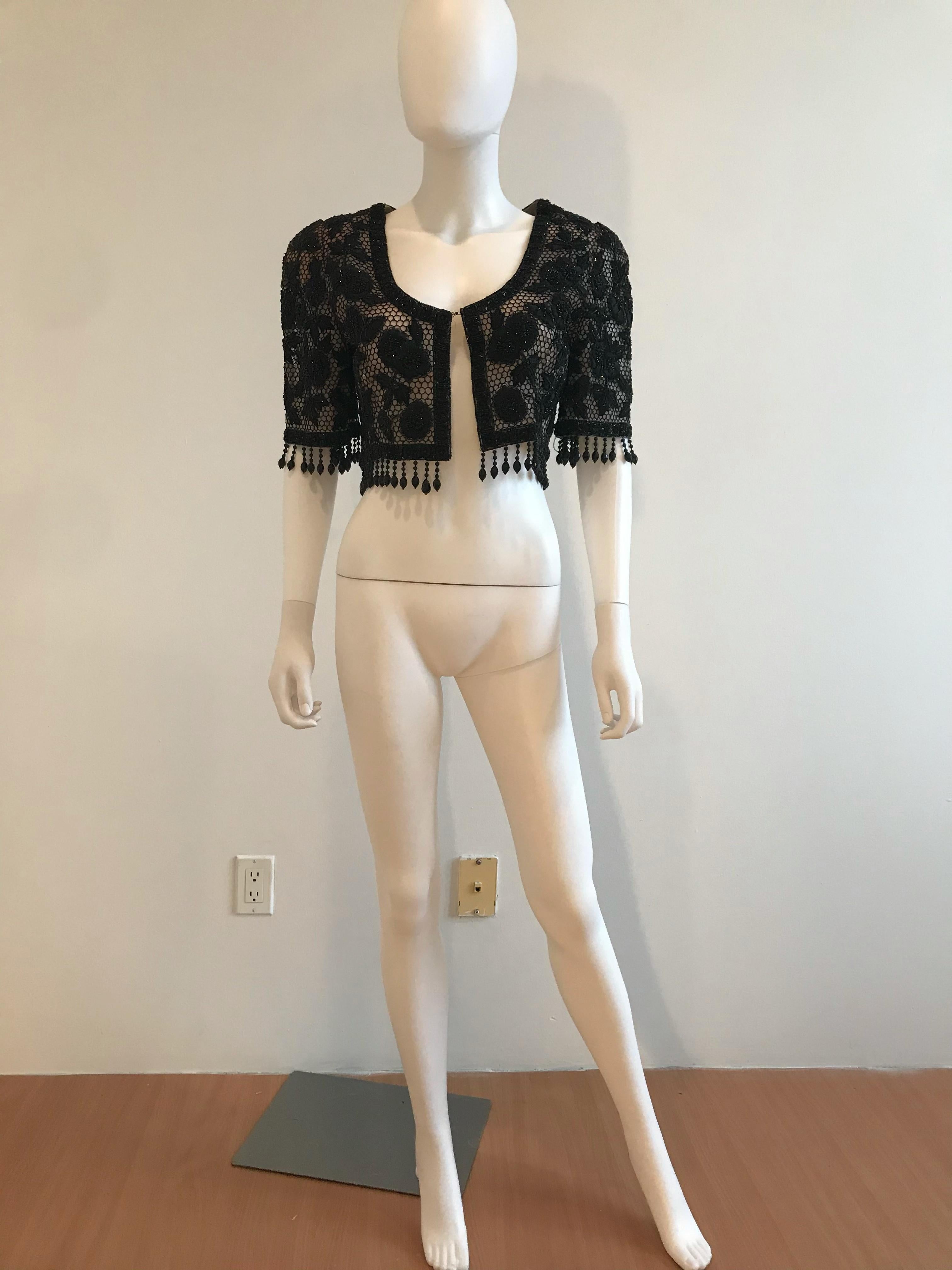 Oscar De La Renta Black Beaded and Embroidered Cropped Evening Bolero. This jacket features threaded embroidered flowers with beaded accents. It also has beaded fringe detailing around the bottom hem and sleeves. The sleeves are quarter sleeves and