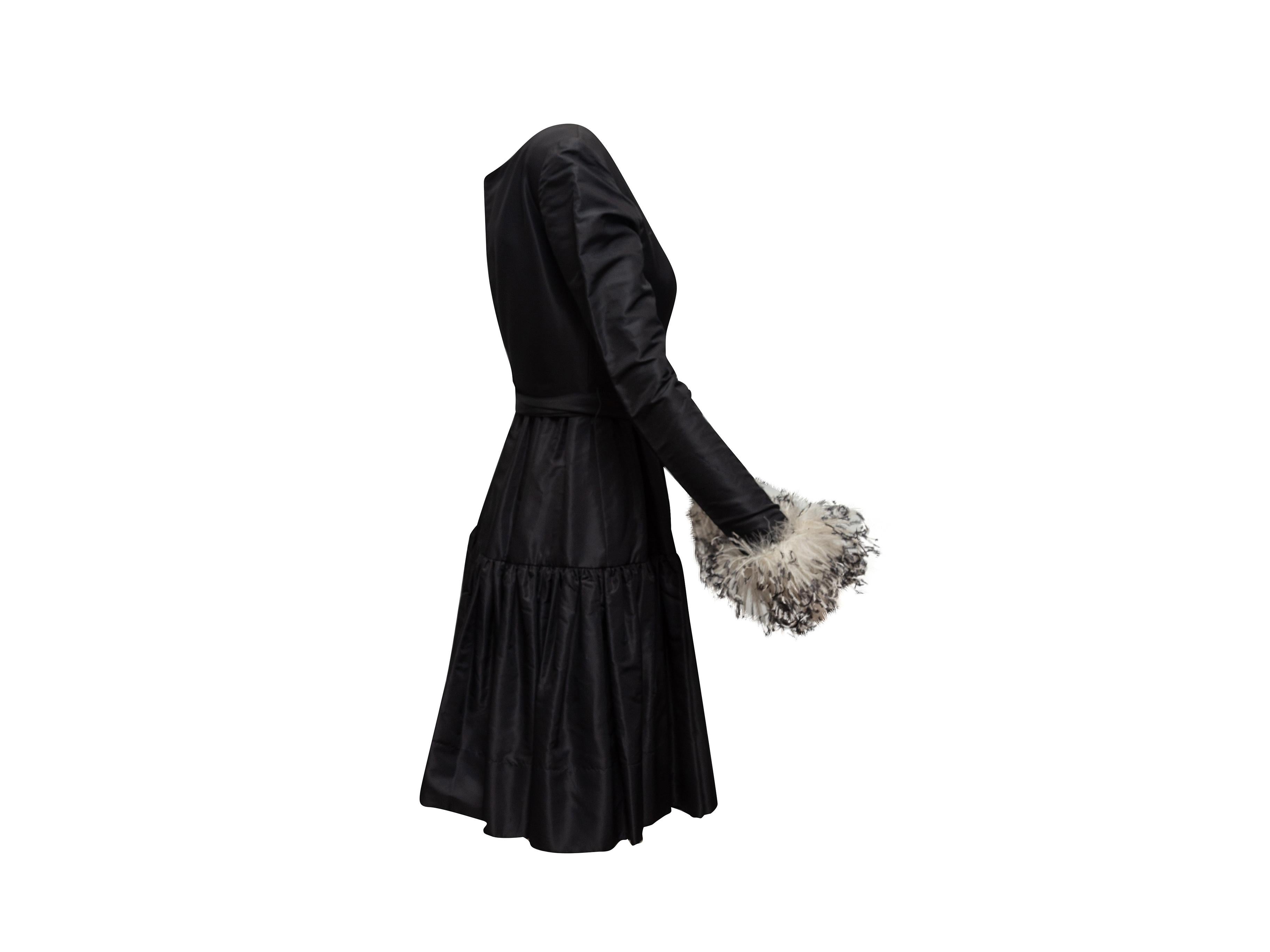 Product details: Vintage black A-line dress by Oscar de la Renta. Scoop neck. Long sleeves featuring feather trim. Sash tie at waist. Zip closure at back. 34