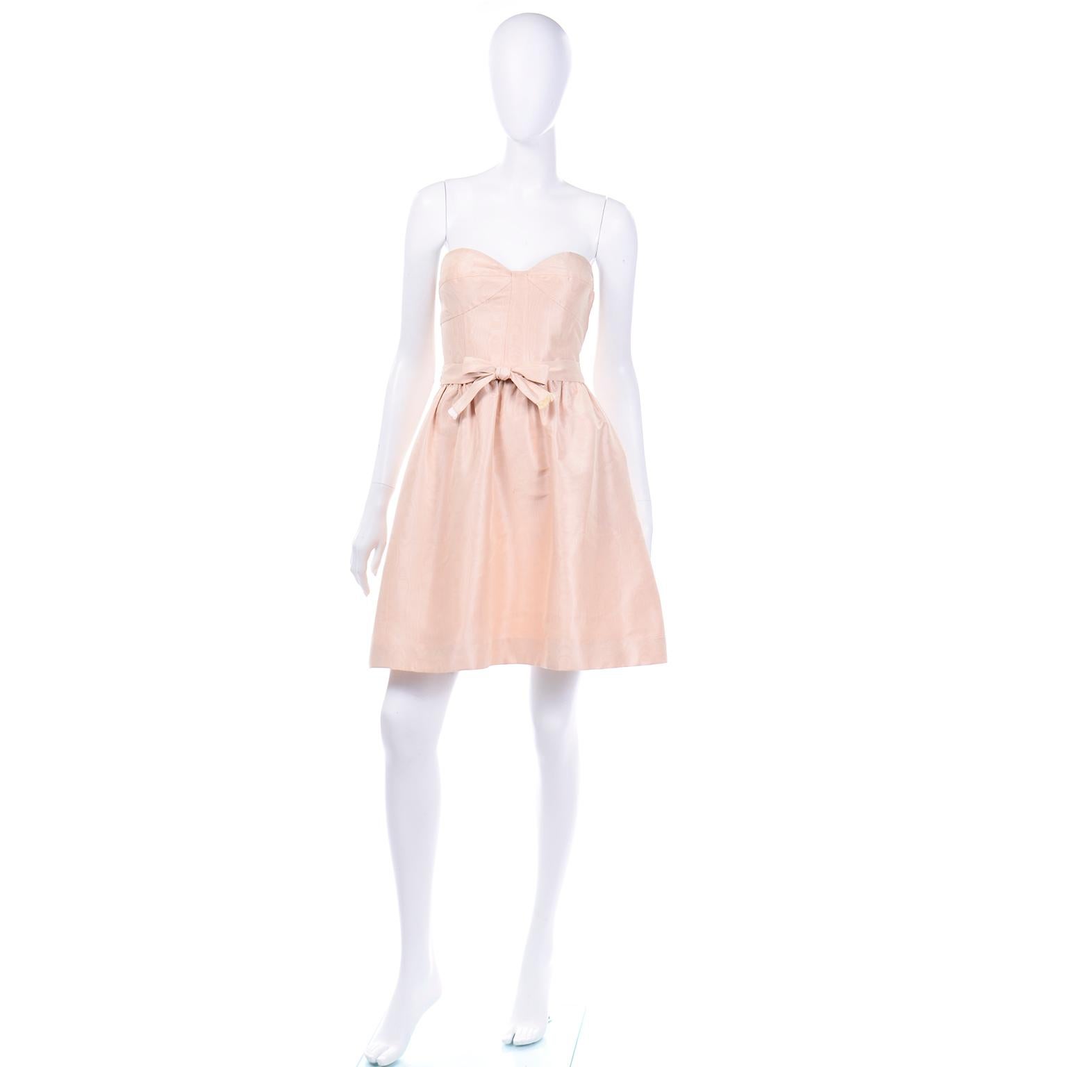 This is a stunning Oscar de la Renta light peach or blush pink wood grain strapless mini dress with a matching belt. This dress is in a beautiful and unique wood grain taffeta fabric and has built-in underwired cups with a corset top. The inside has