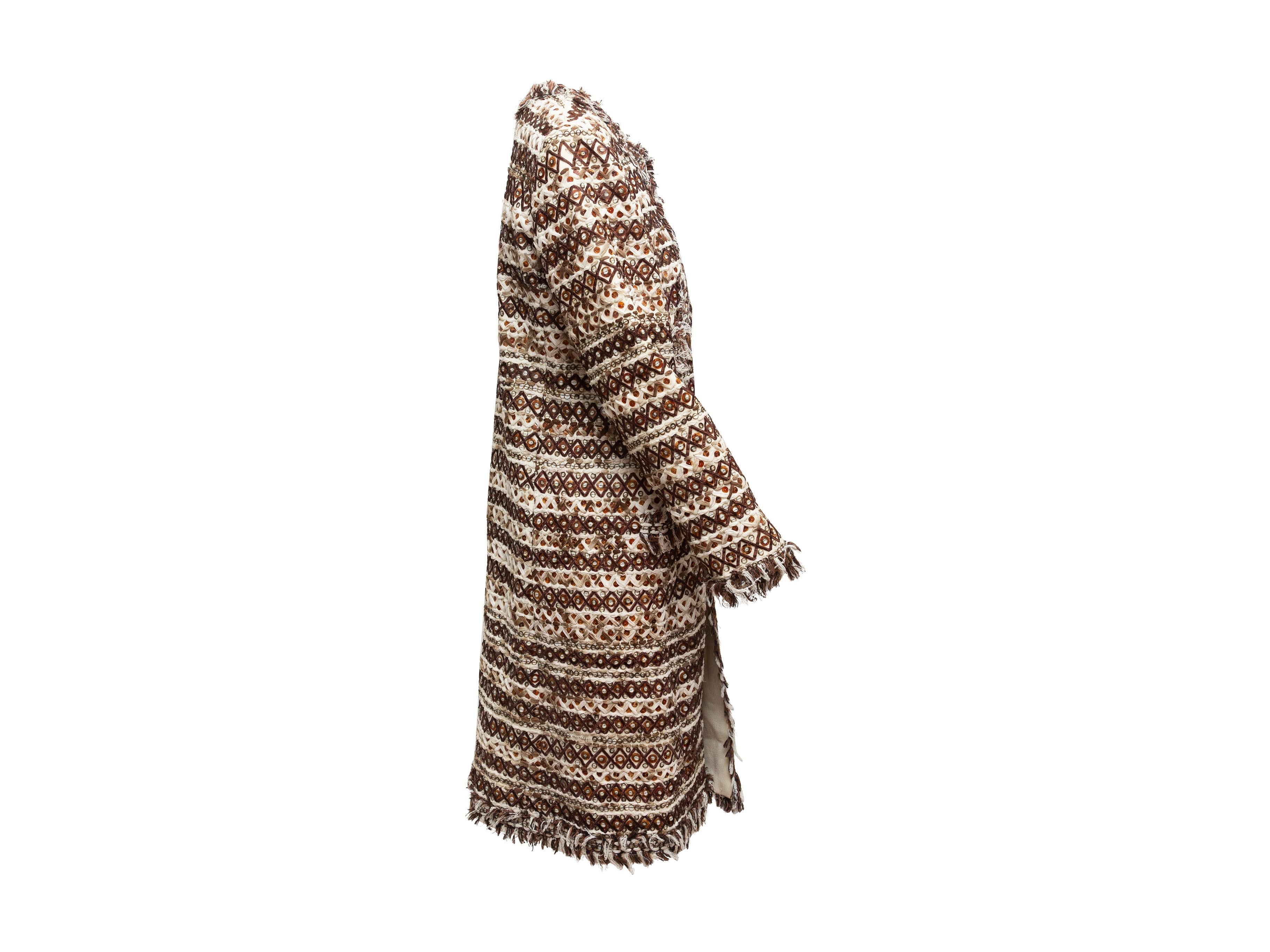 Product details: Brown and cream textured long coat by Oscar de la Renta. Fringe trim and sequin embellishments throughout. Four pockets at front. Closure at center front. 40