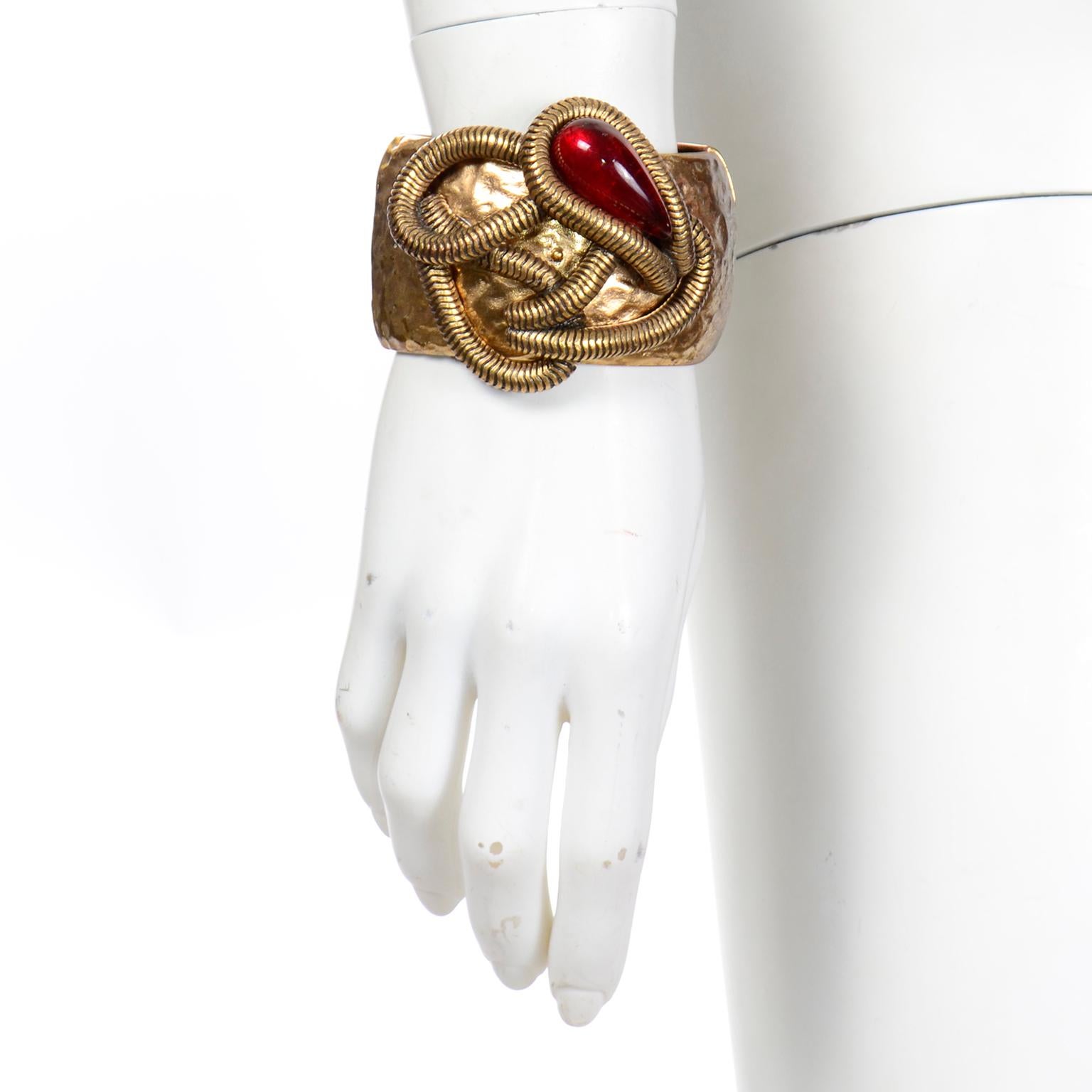 This is a stunning vintage Oscar de la Renta brutalist style Clamper bracelet in a hammered gold metal with a teardrop shaped red cabochon. There are rich variations in the color, creating dimension and we love the twisted snake chain metal that