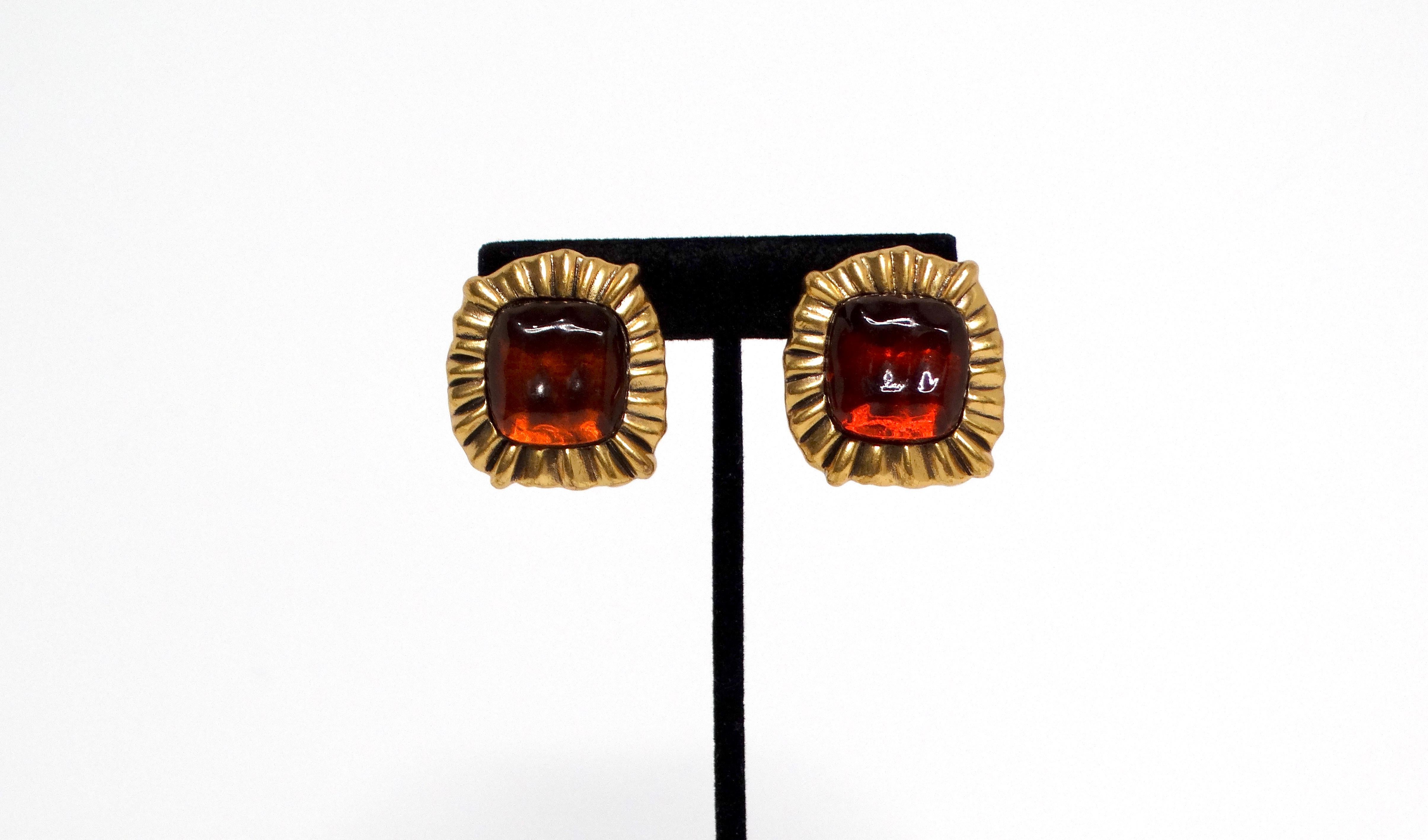 The Oscar de la Renta Circa 1990s red and orange jewel-tone clip-on earrings are a stunning statement piece, perfect for adding a splash of vibrant color to any ensemble. These square-shaped earrings feature a luxurious gold-tone frame, which