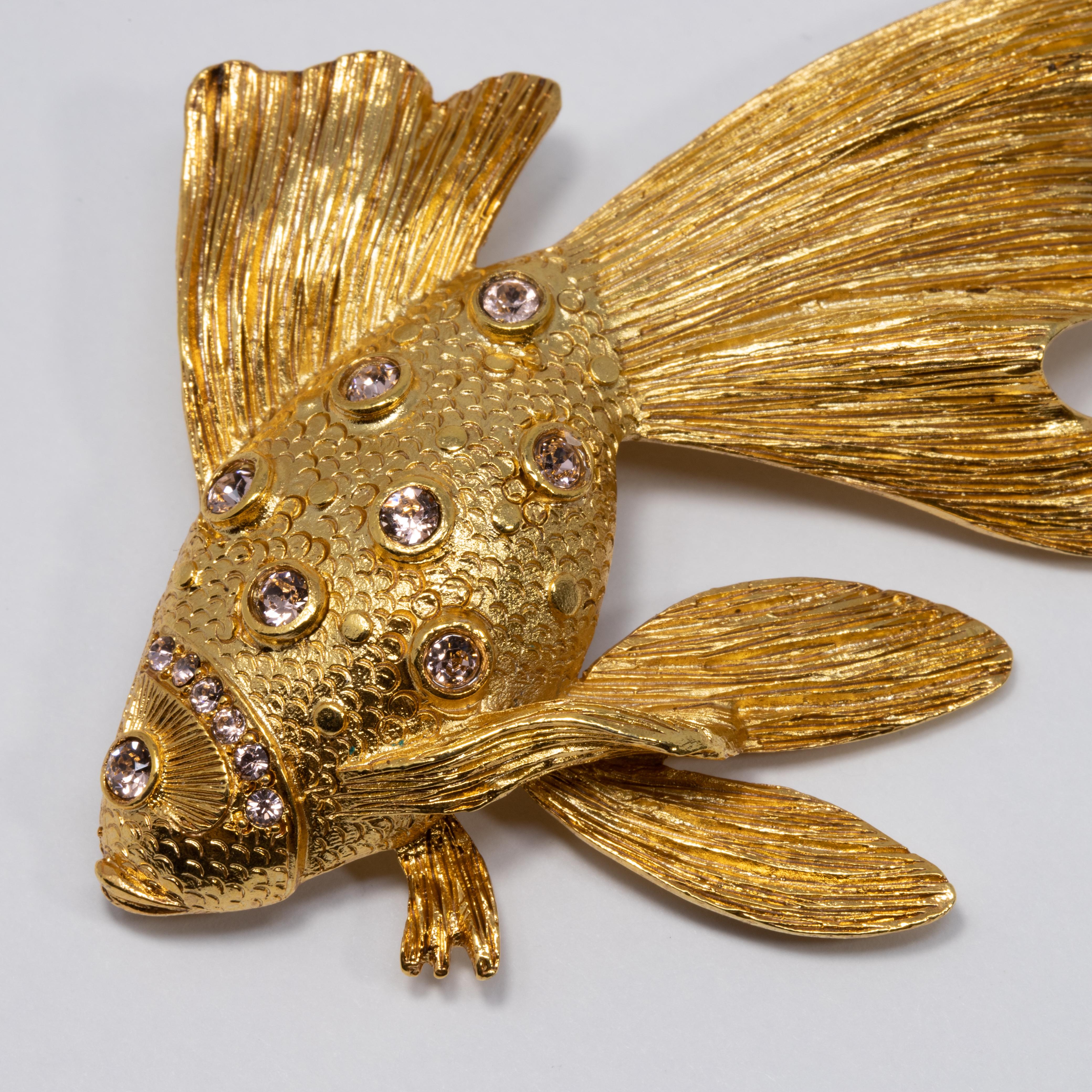 Perfectionnez votre look avec cette broche poisson en métal doré sertie de cristaux Swarovski étincelants. Pour une esthétique marine parfaite !

Poinçons : Oscar de la Renta, Made in USA