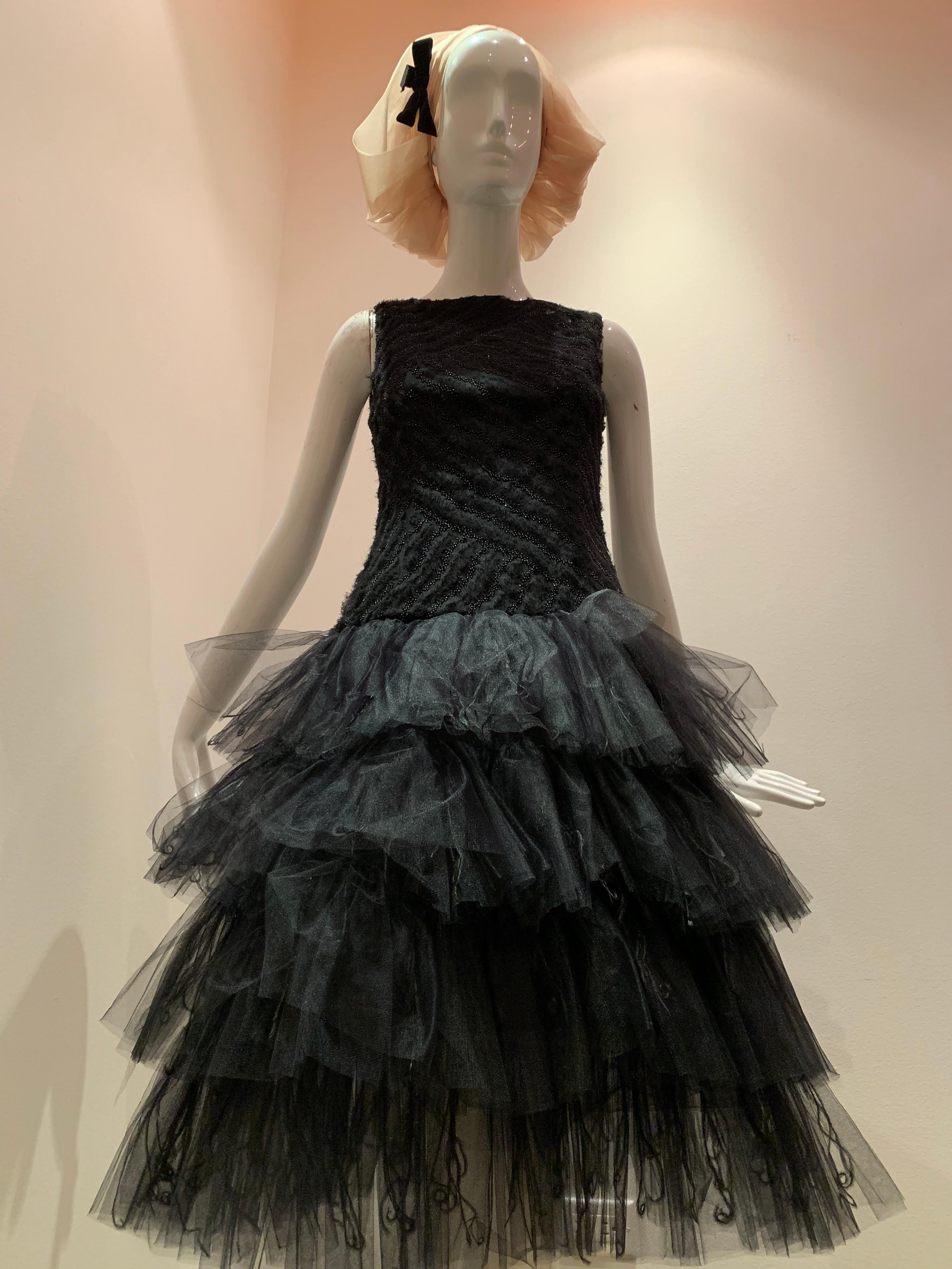 A contemporary Oscar de la Renta ballet-inspired dropped-waist, sleeveless black cocktail dress with multi-tiered tulle skirt embellished with curled ostrich feathers. The ballet neck bodice is embellished with beaded diagonal stripes and gathered