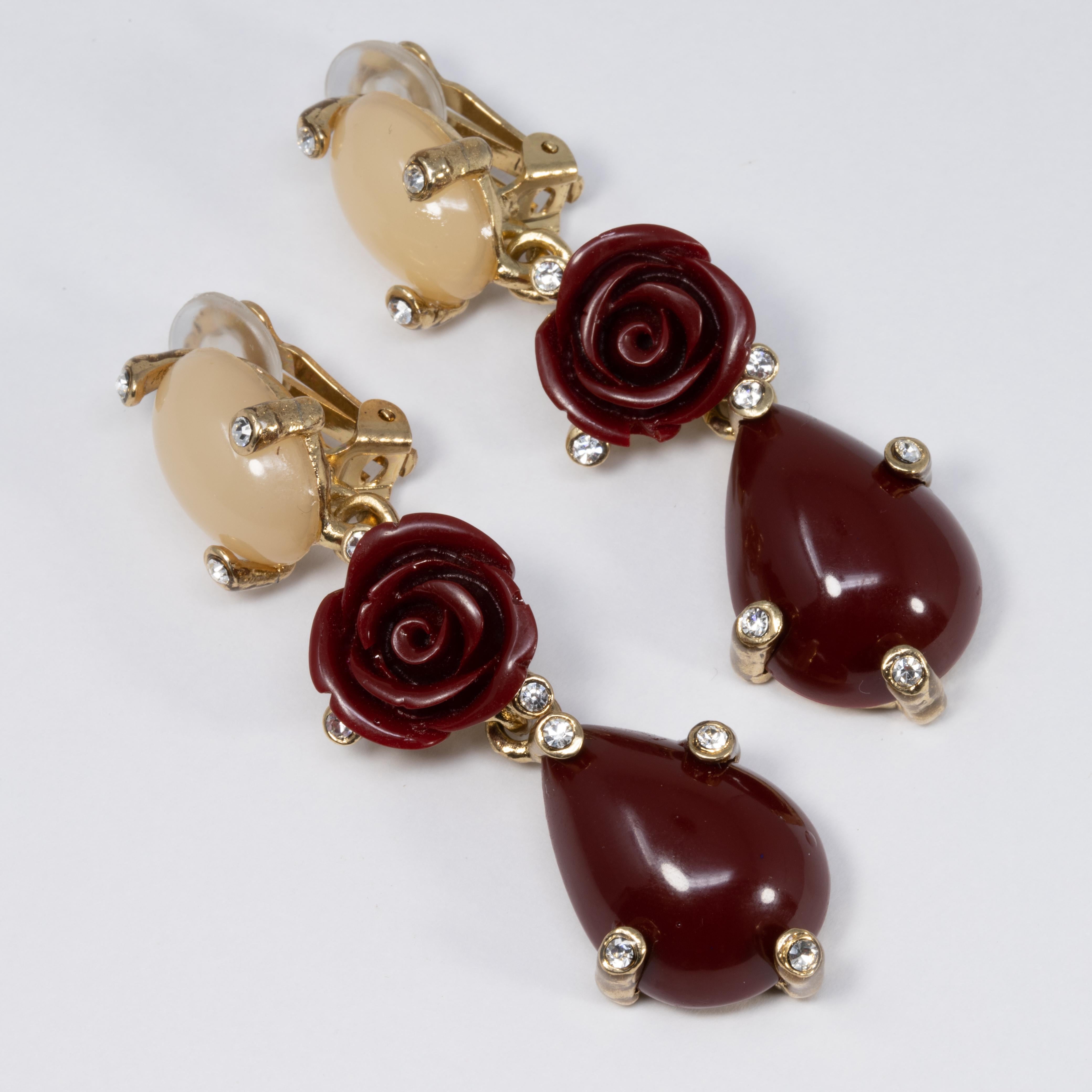 A pair of dangling clip on earrings with gorgeous floral themes by Oscar de la Renta. Each earring features two prong set cabochons and a red rose, accented with clear crystals.

Hallmarks: Oscar de la Renta, Made in USA