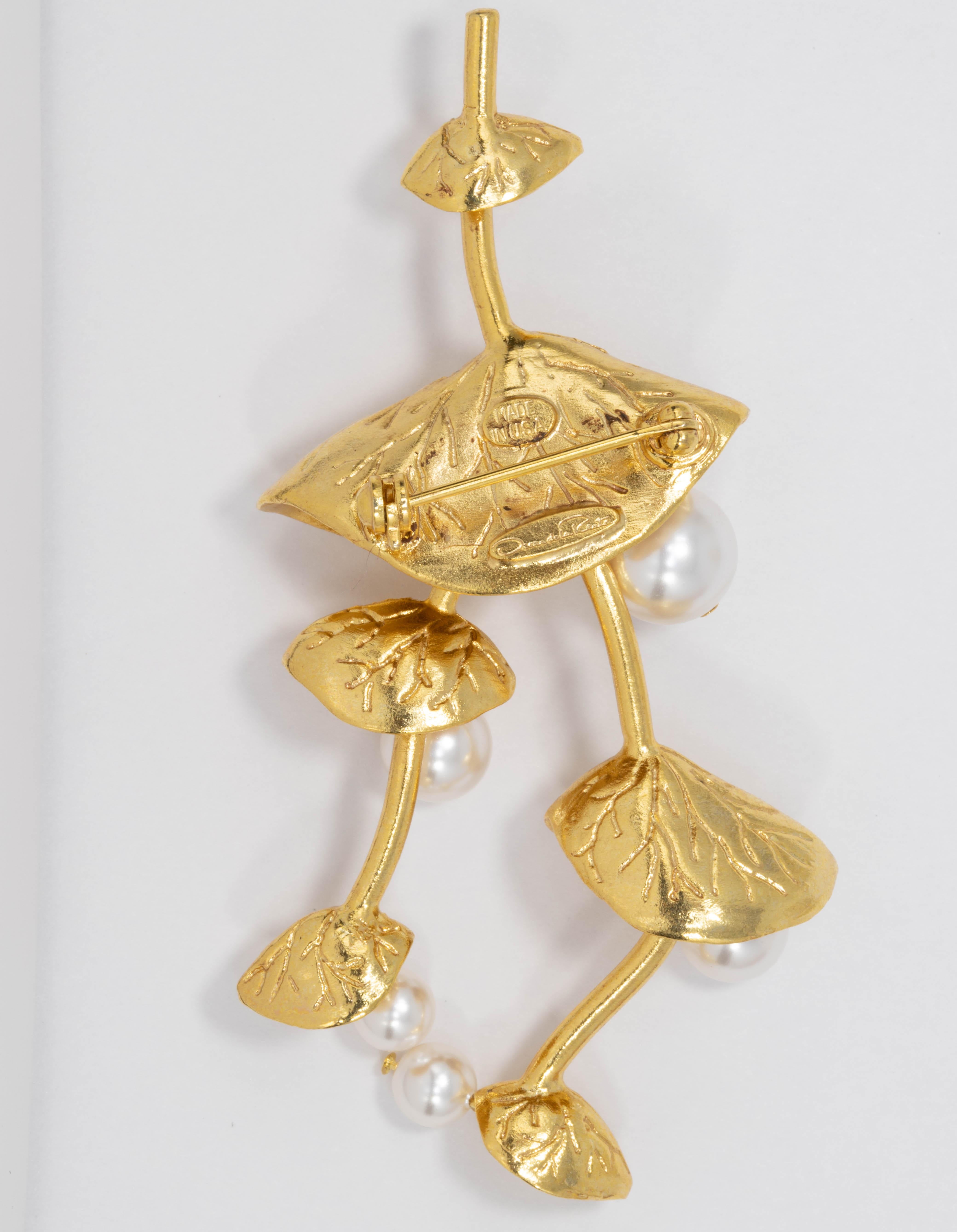 A stylish Oscar de la Renta pin brooch, featuring branches of flowing flowers, accented with dangling faux pearls.

Gold plated.

Tags, Marks, Hallmarks: Oscar de la Renta, Made in USA