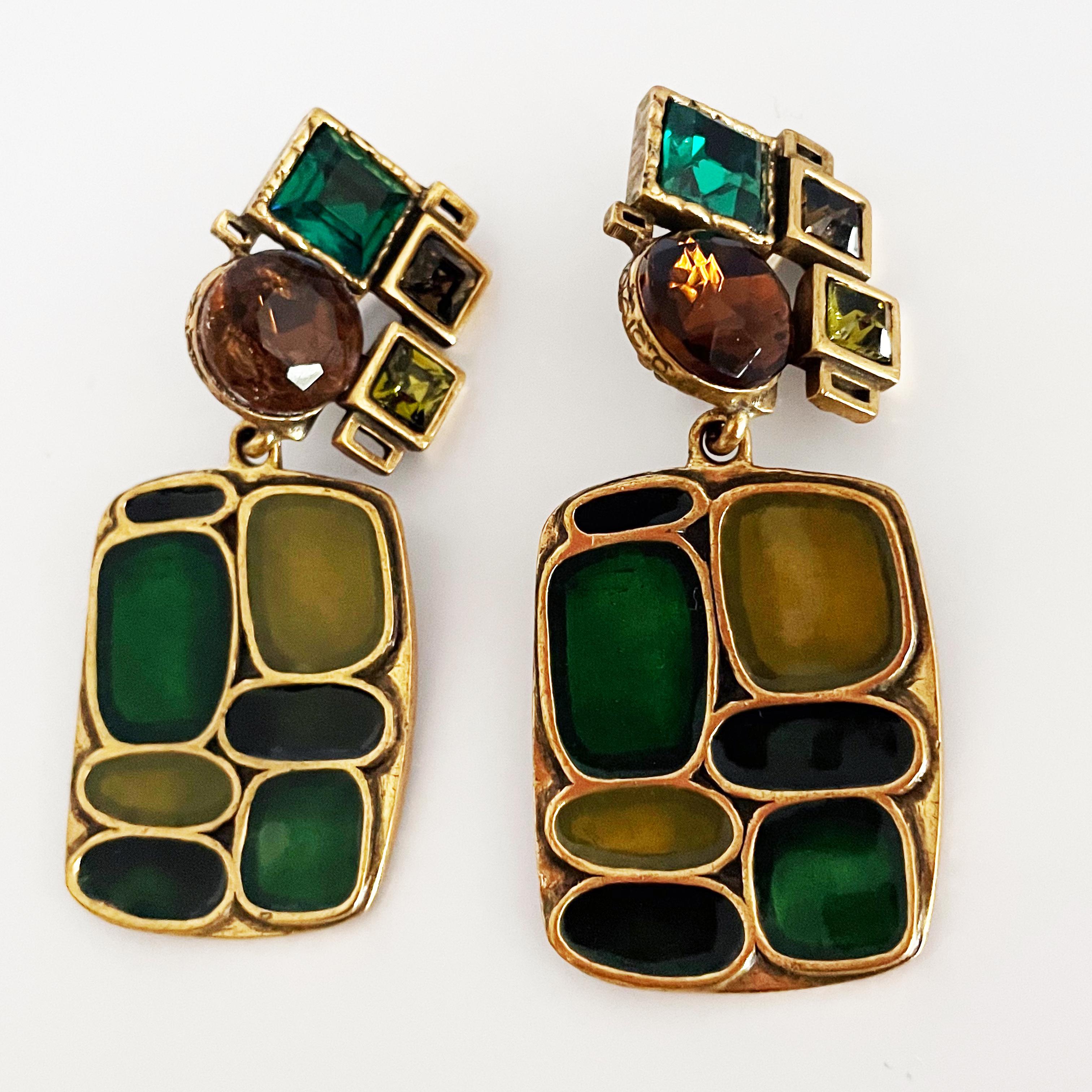 Oscar de la Renta modernist dangle earrings, most likely made in the 1980s.  Made from brass-hued metal, they feature  modernist shapes and crystals in shades of lime, emerald and topaz.  

These fabulous designer earrings are made to elevate your