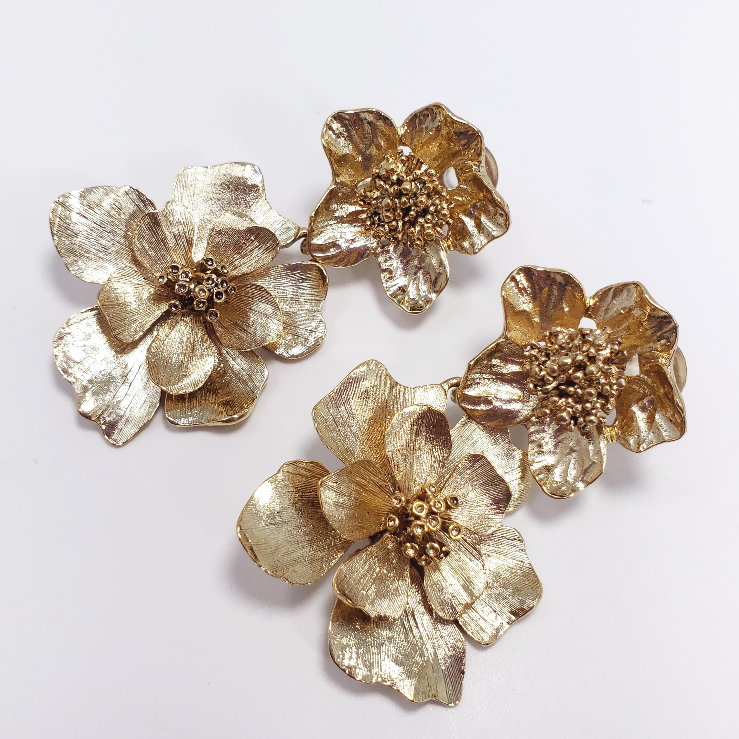 Loud and vibrant dangling clip-ons, featuring two dangling flowers on each earring, plated in 22K antique Russian gold. These Oscar de la Renta gold bold flower earrings definitely live up to their name!

6.5cm in length. The larger flower motif is