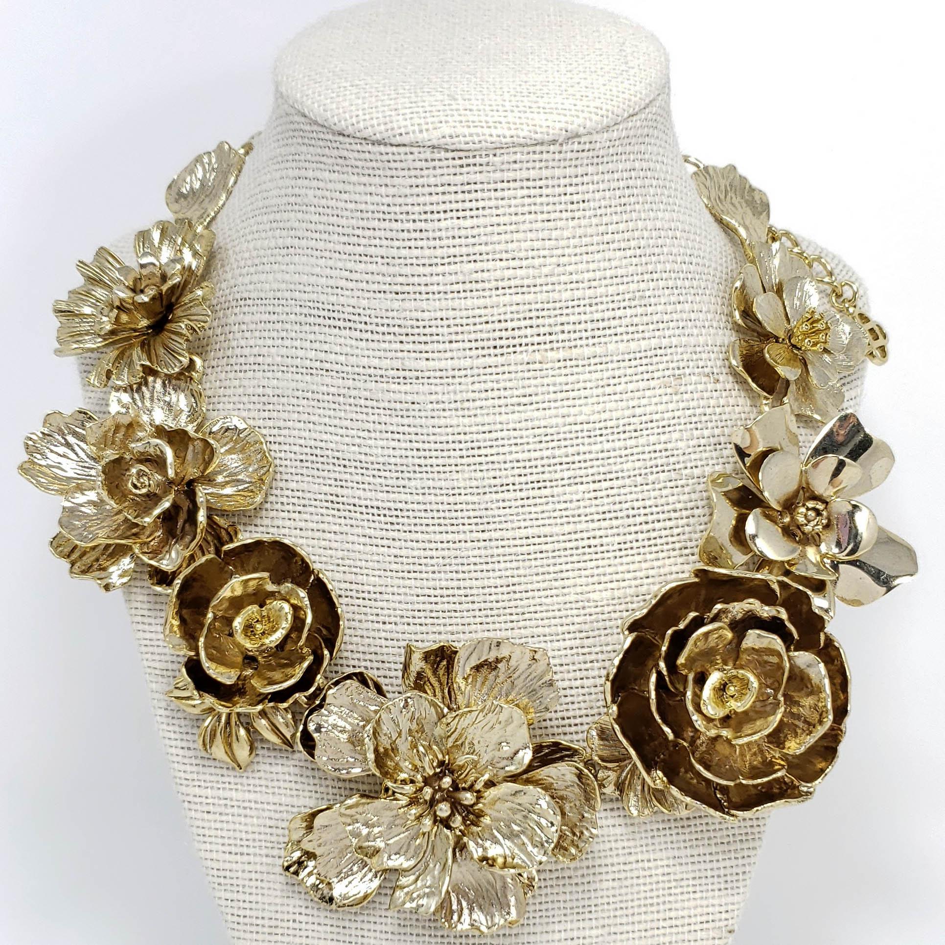 Bold, feminine design! This statement flower link necklace by Oscar de la Renta showcases a strand of blossoming flowers that rest on the collarbones.

Antique-style textured gold-plated finish.

Hallmarks: Oscar de la Renta, Made in USA

15.75 in /