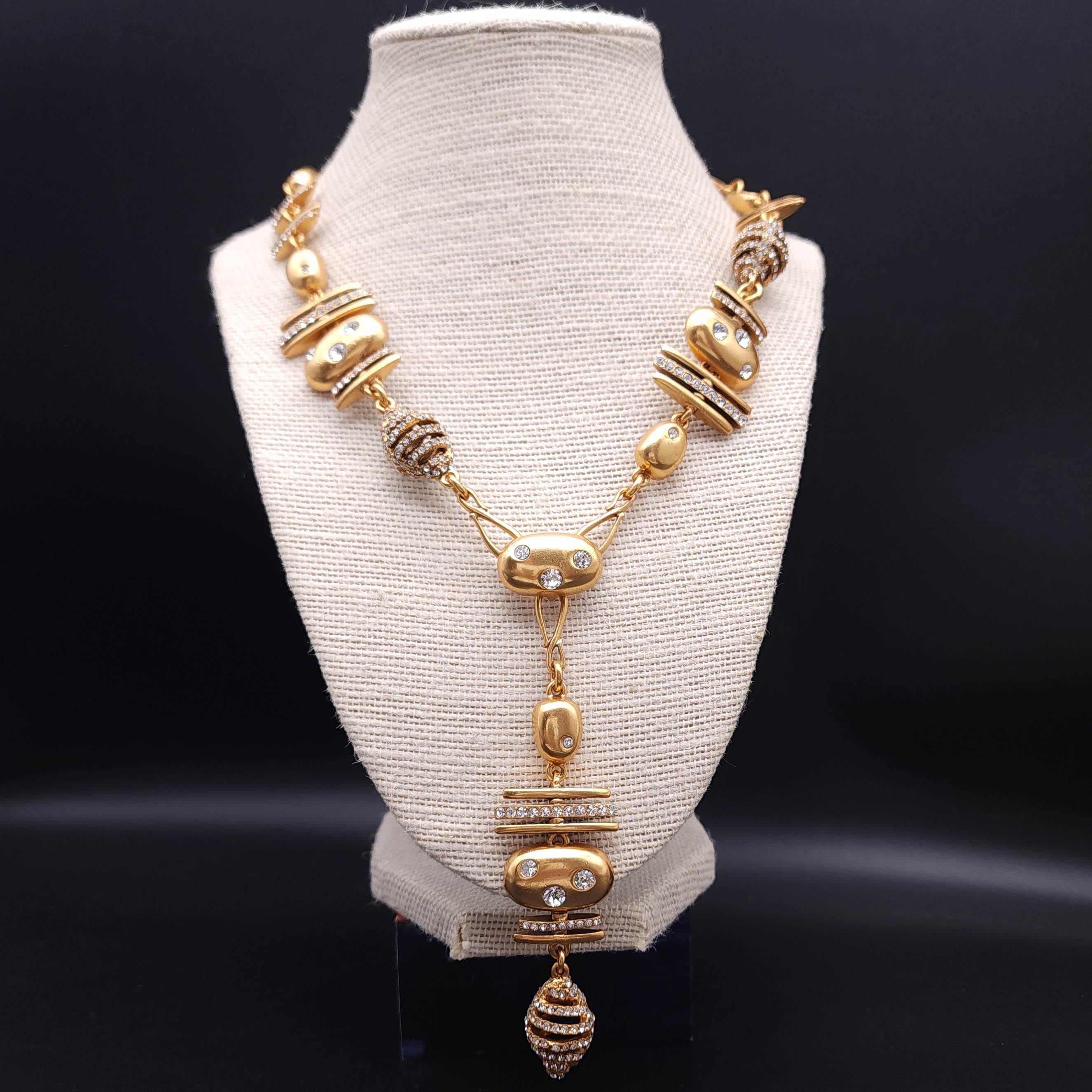 Una splendida collana Oscar De La Renta che sfoggia un design unico in stile charme con un ciondolo a goccia che cattura l'attenzione. Lucida tonalità oro con elementi geometrici alternati e accenti di cristallo incastonati. 

La collana si chiude