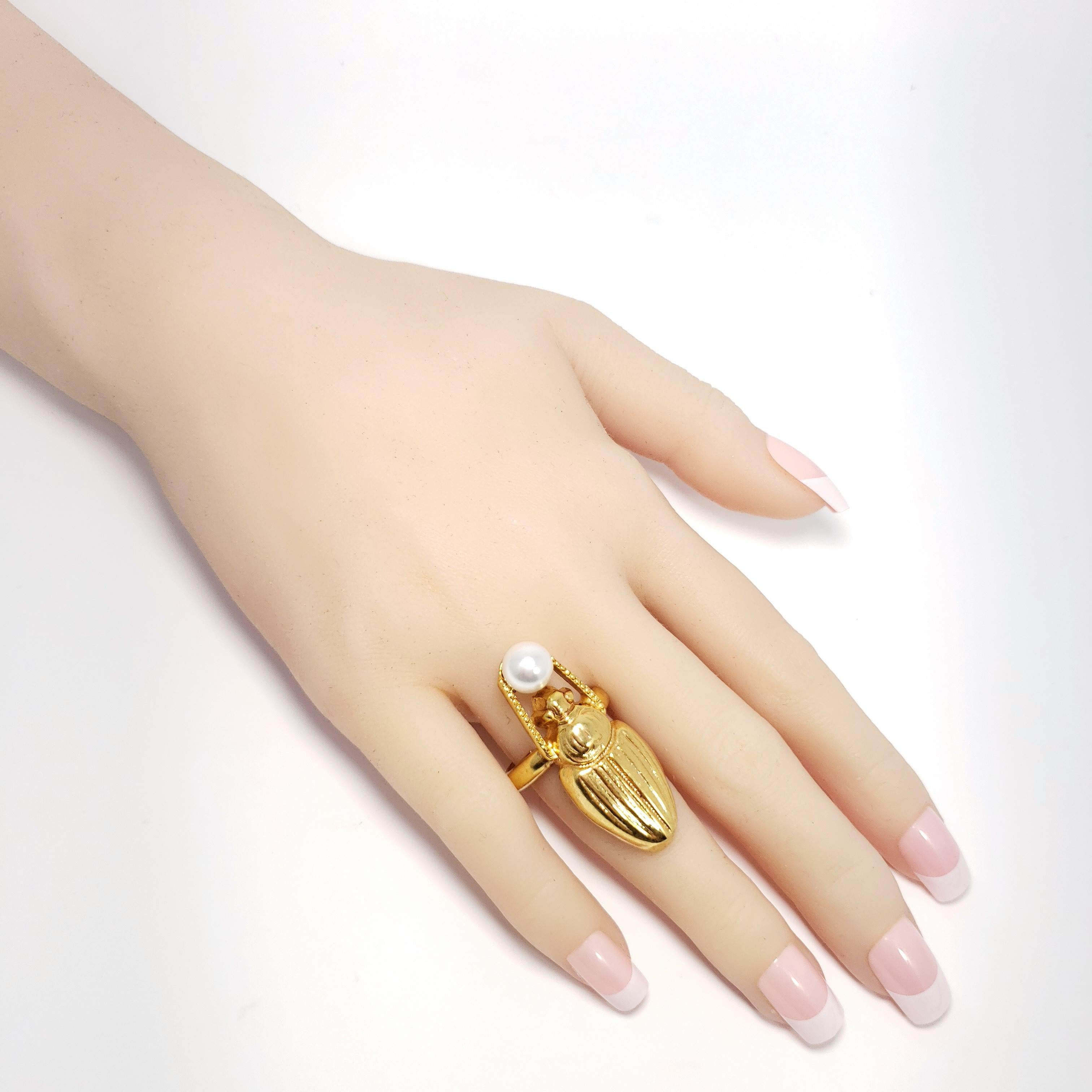 Oscar de la Renta cocktail ring, featuring a polished gold scarab accented with a single faux pearl.

Adjustable sizes 5 to 8.5

Tags, Marks, Hallmarks: Oscar de la Renta, Made in USA
