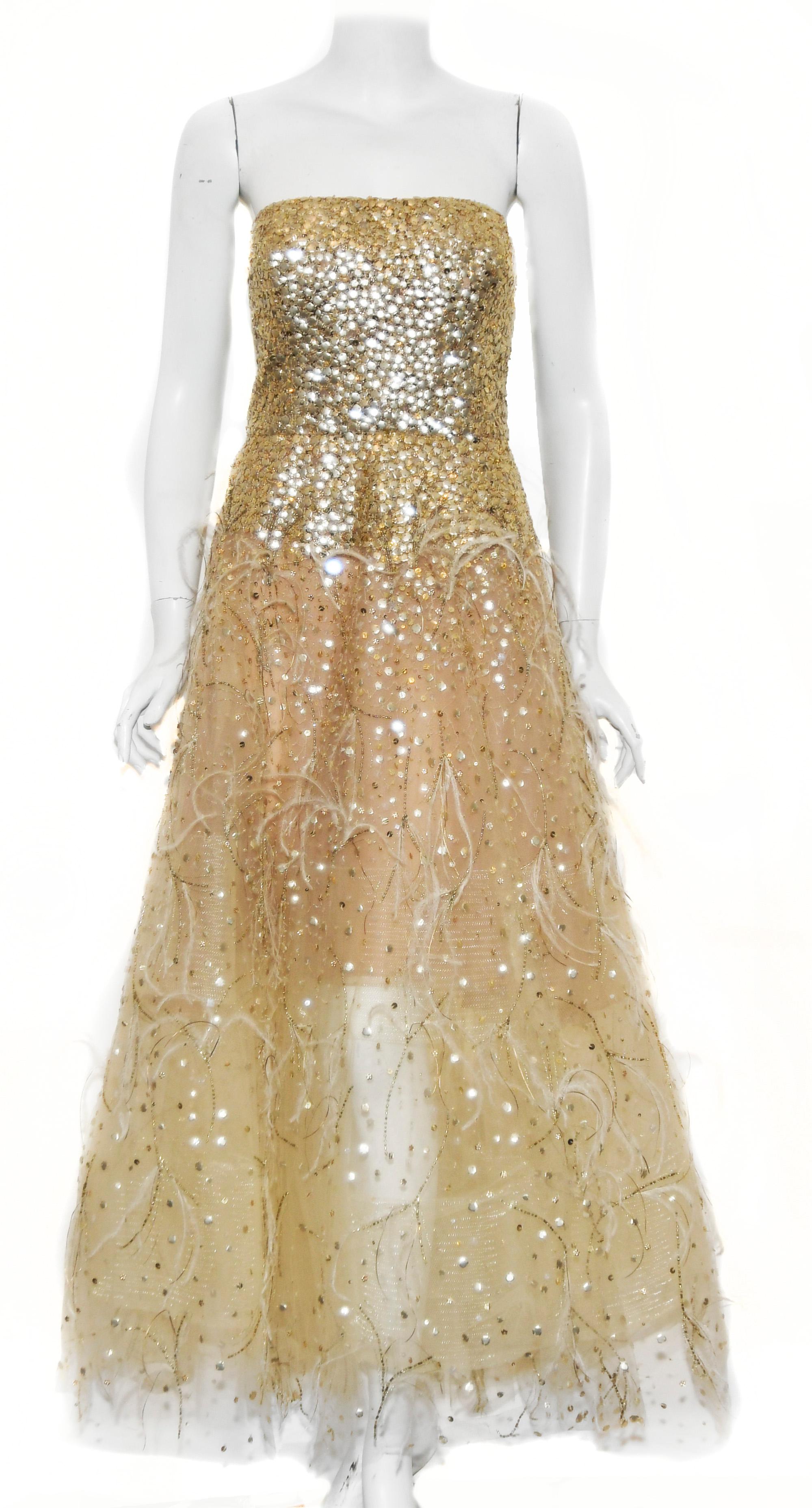 Oscar de la Renta gold tone sequin strapless gown incorporating ostrich feather accents from the waist down to the hem.  The bodice of this gown is bursting with sequins and the sequins diminish as it cascades down the skirt.  The strapless top