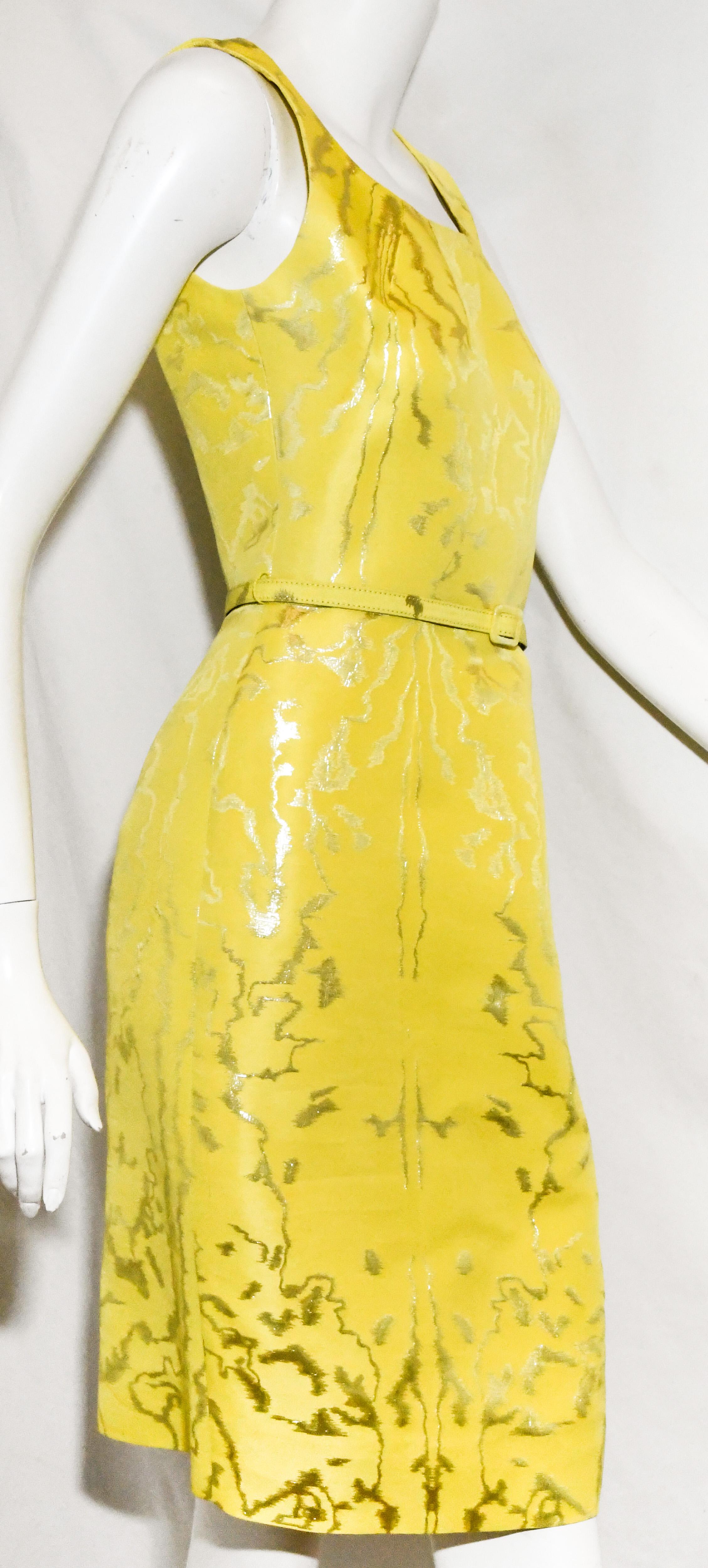 Oscar de la Renta lemon brocade textured cocktail dress incorporates metallic silver thick threads throughout. 
With a square scoop neck this abstract brocade print dress includes a thin covered belt.  At the back, a long zipper and a small vent at