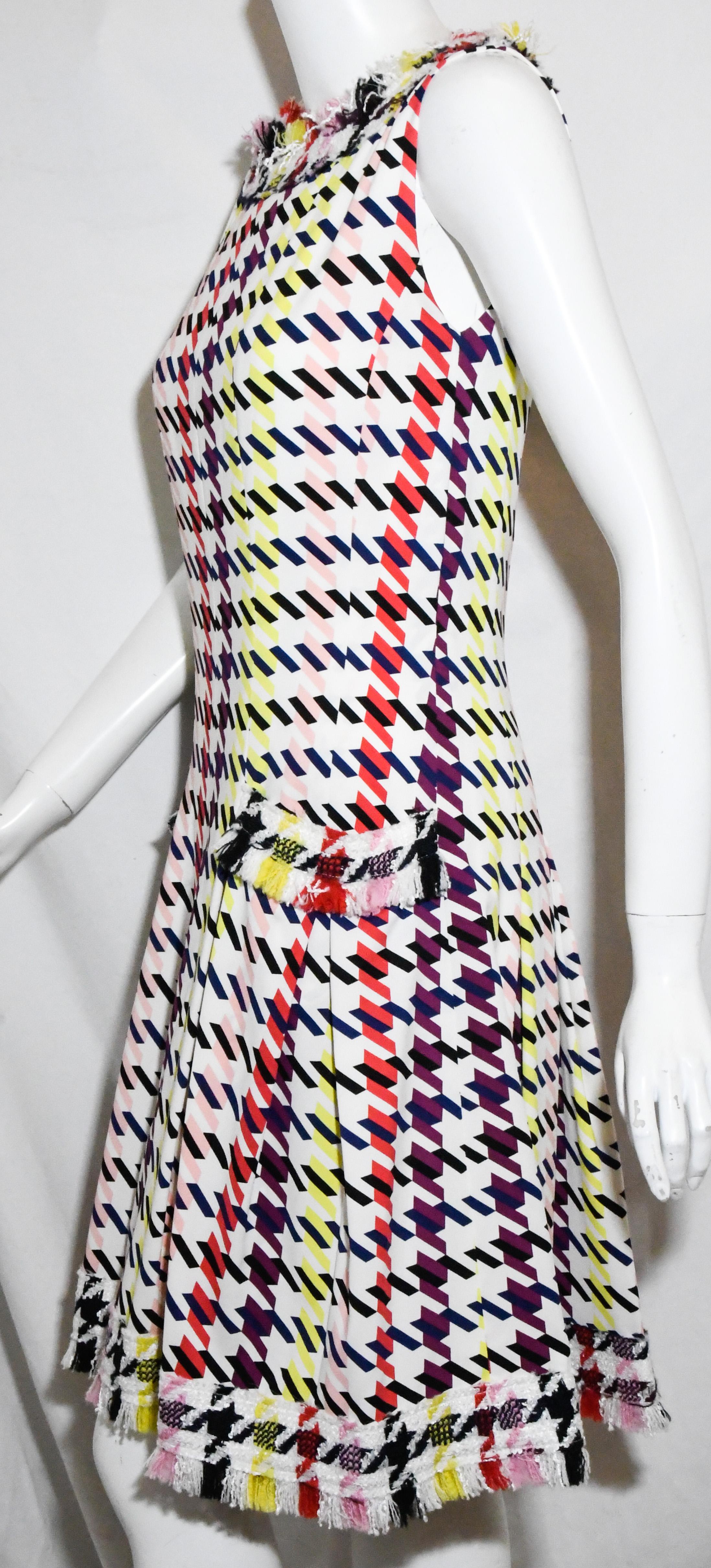 Oscar de la Renta multi color tweed dress includes a striped graphic geometric design.   Finished with structural pleated skirt and multiple layered fringes around the neck, top of pockets and hem in vibrant colors.   This sleeveless dress contained