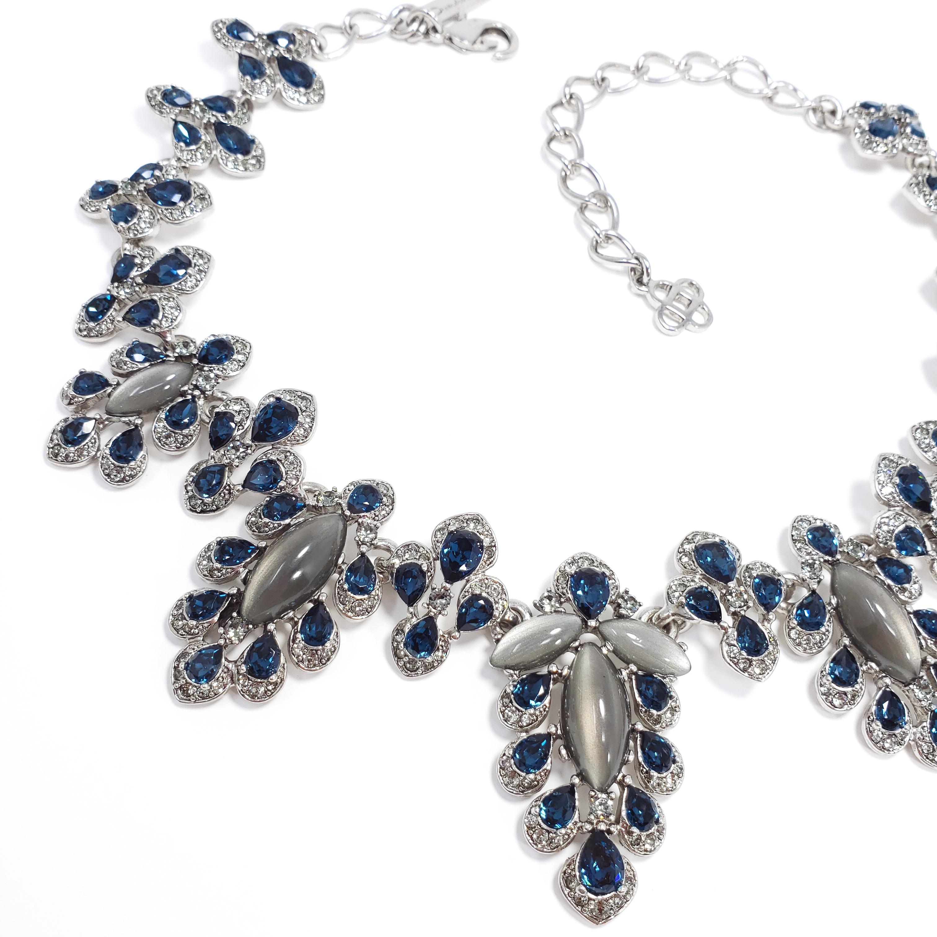 An Oscar de la Renta necklace from the parlor collection. Features links of parlor motifs, composed of dark blue and gray/clear crystals with centerpiece gray moonglow cabochons. Silvertone setting.

Length: 39.5 cm length + 9.5 cm extension