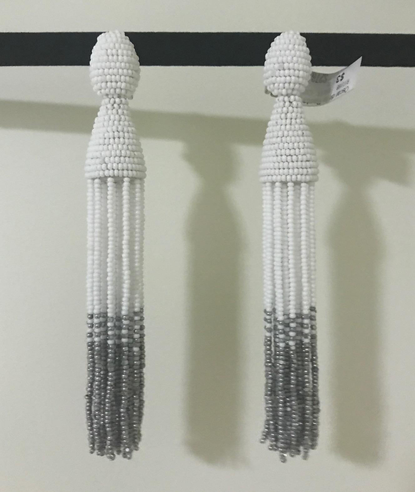 Oscar de la Renta white and muted silver beaded tassel earrings. Clip backs with clear rubber inserts for comfort.

Measure approximately 5 1/2
