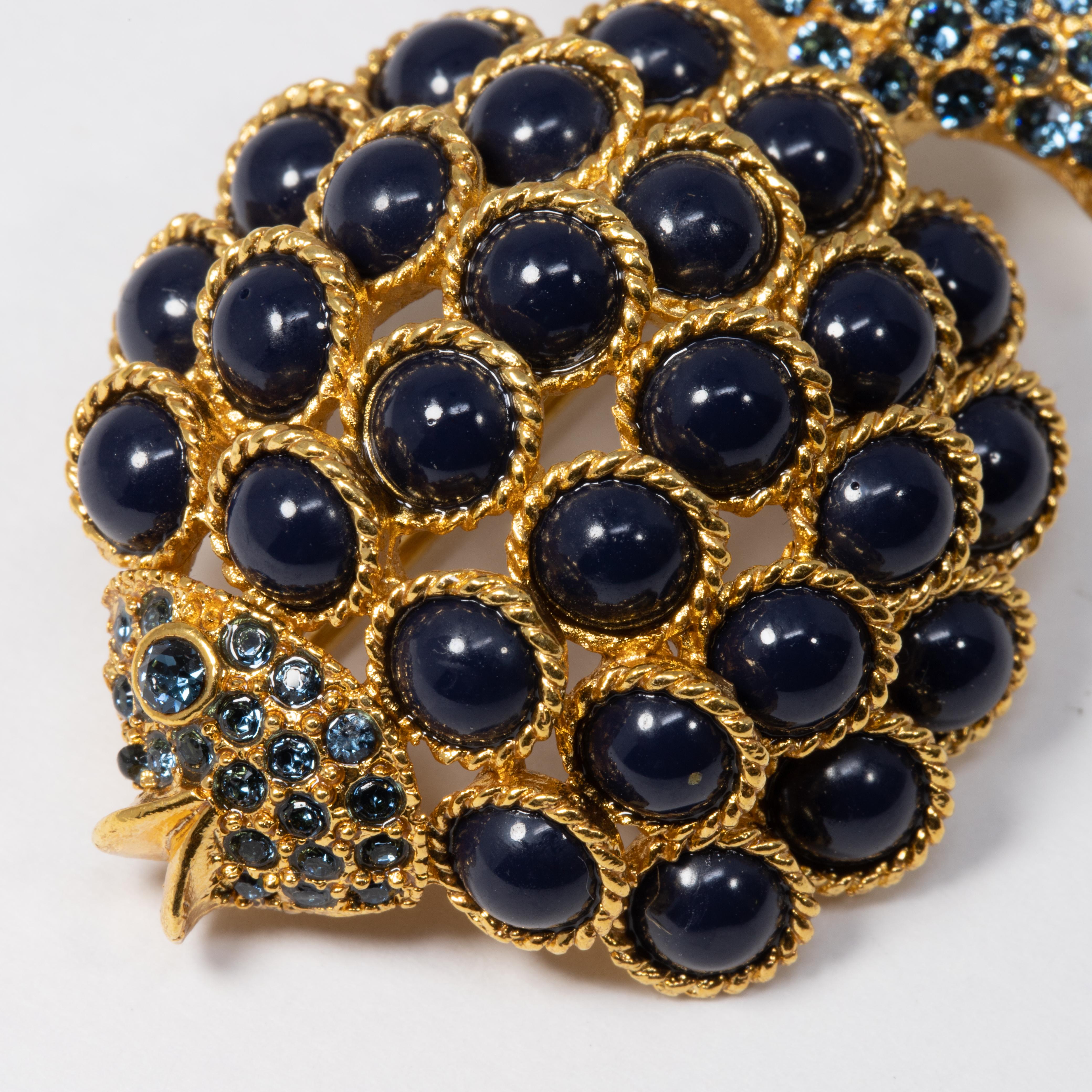 Le poisson en or d'Oscar de la Renta est décoré de cabochons et de cristaux bleu foncé. Ajoutez une touche sophistiquée à votre tenue !

Poinçons : Oscar de la Renta, Made in USA