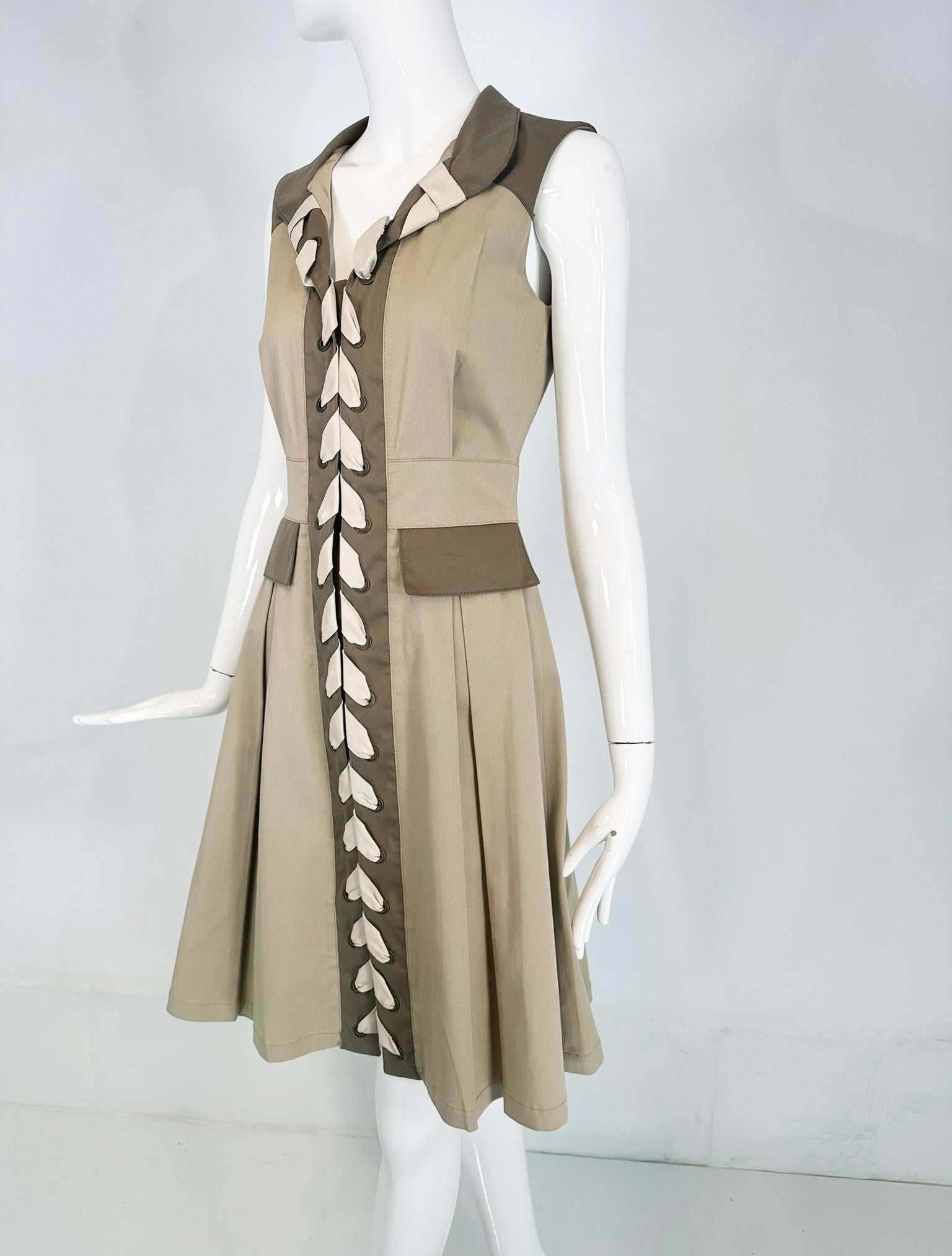 Oscar de la Renta Resort 2011 two tone khaki twill & leather safari style dress. Pale tan khaki dress with army green pocket flaps & facings. Sleeveless dress has a notched lapel collar, decorative cream leather lacing wound through antique brass