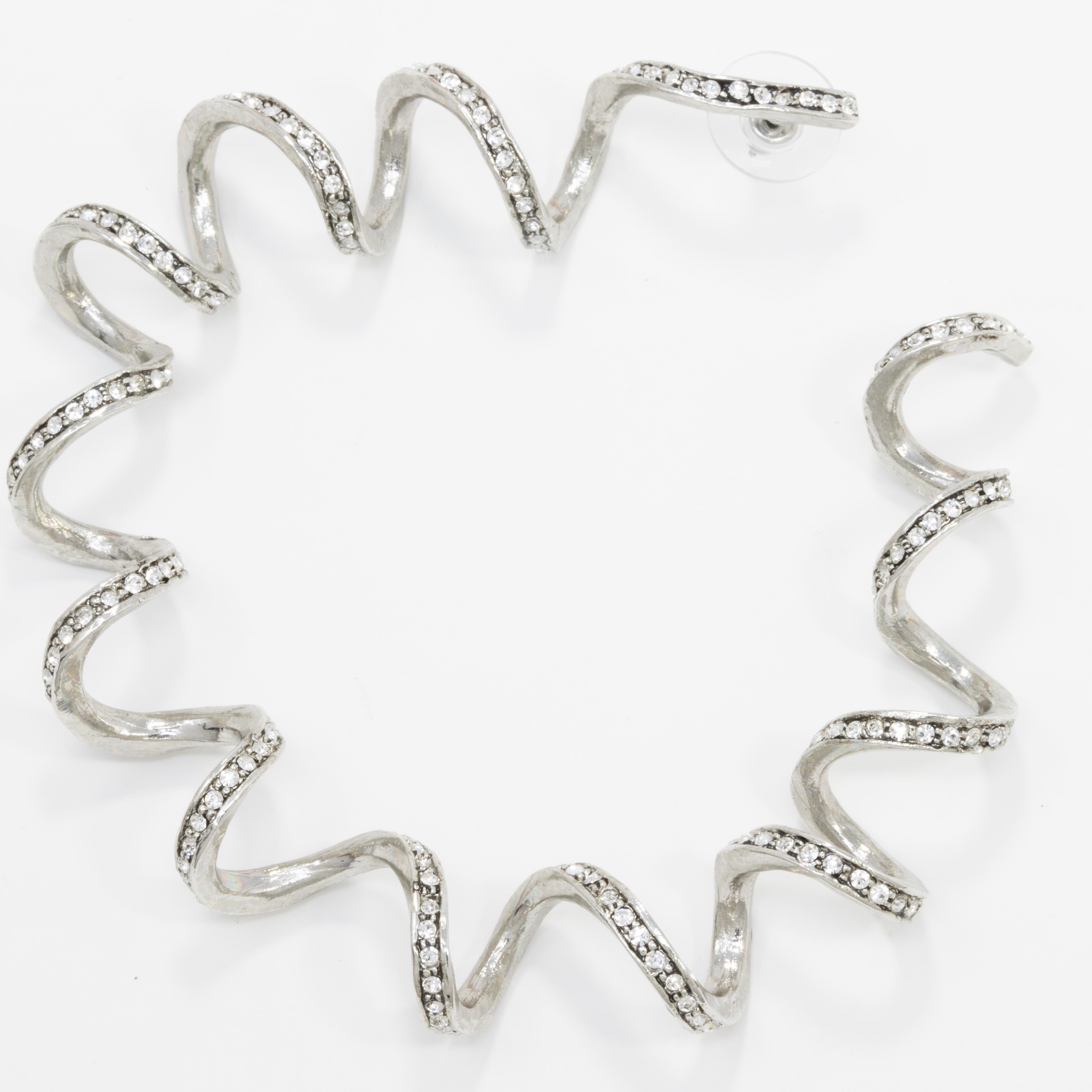 Bold twisted curl hoop earrings accented with clear Swarovski crystals. Add a sophisticated silver glow to your outfit!

By Oscar de la Renta.

Rhodium plated. Post backs.

Hallmarks: none