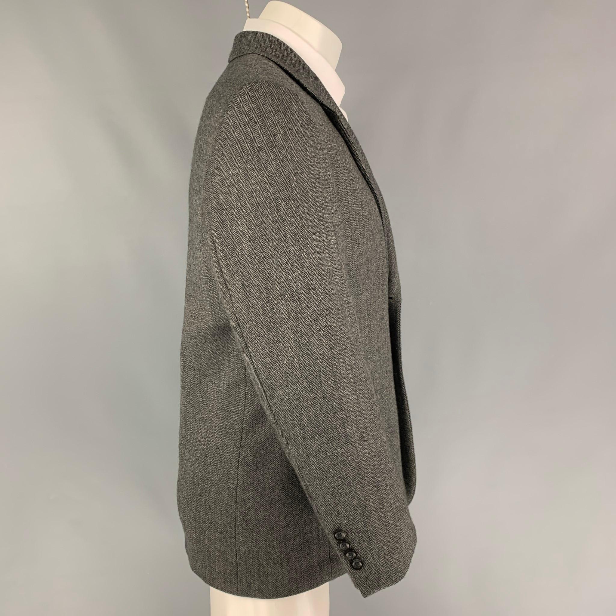 OSCAR DE LA RENTA sport coat comes in a grey & black herringbone wool featuring a notch lapel, flap pockets, and a double button closure. 

Very Good Pre-Owned Condition.
Marked: 38 S

Measurements:

Shoulder: 18.5 in.
Chest: 38 in.
Sleeve: 24