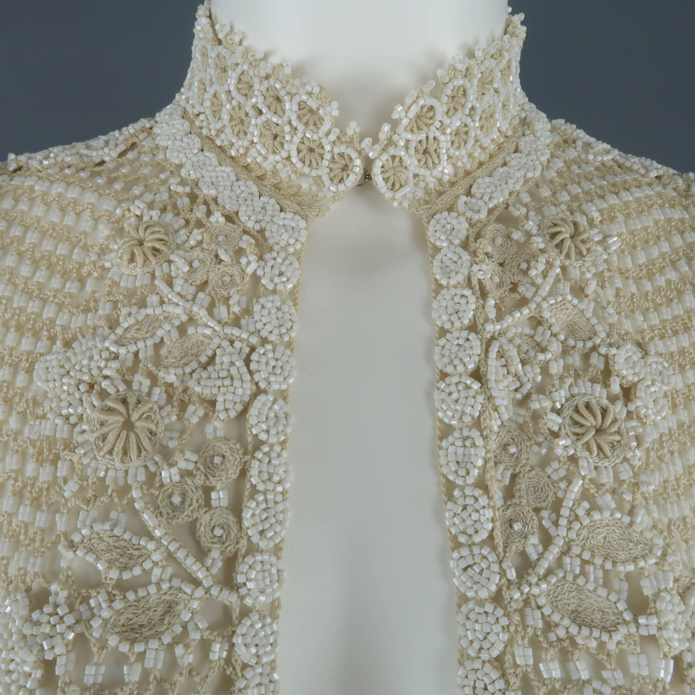 OSCAR DE A RENTA vest comes in a light beige floral patterned white beaded macrame mesh crochet knit with hook eye closures, stand up collar, and ball mesh trim. Discoloration inside collar.
 
Good Pre-Owned Condition.
Marked: (no size)
