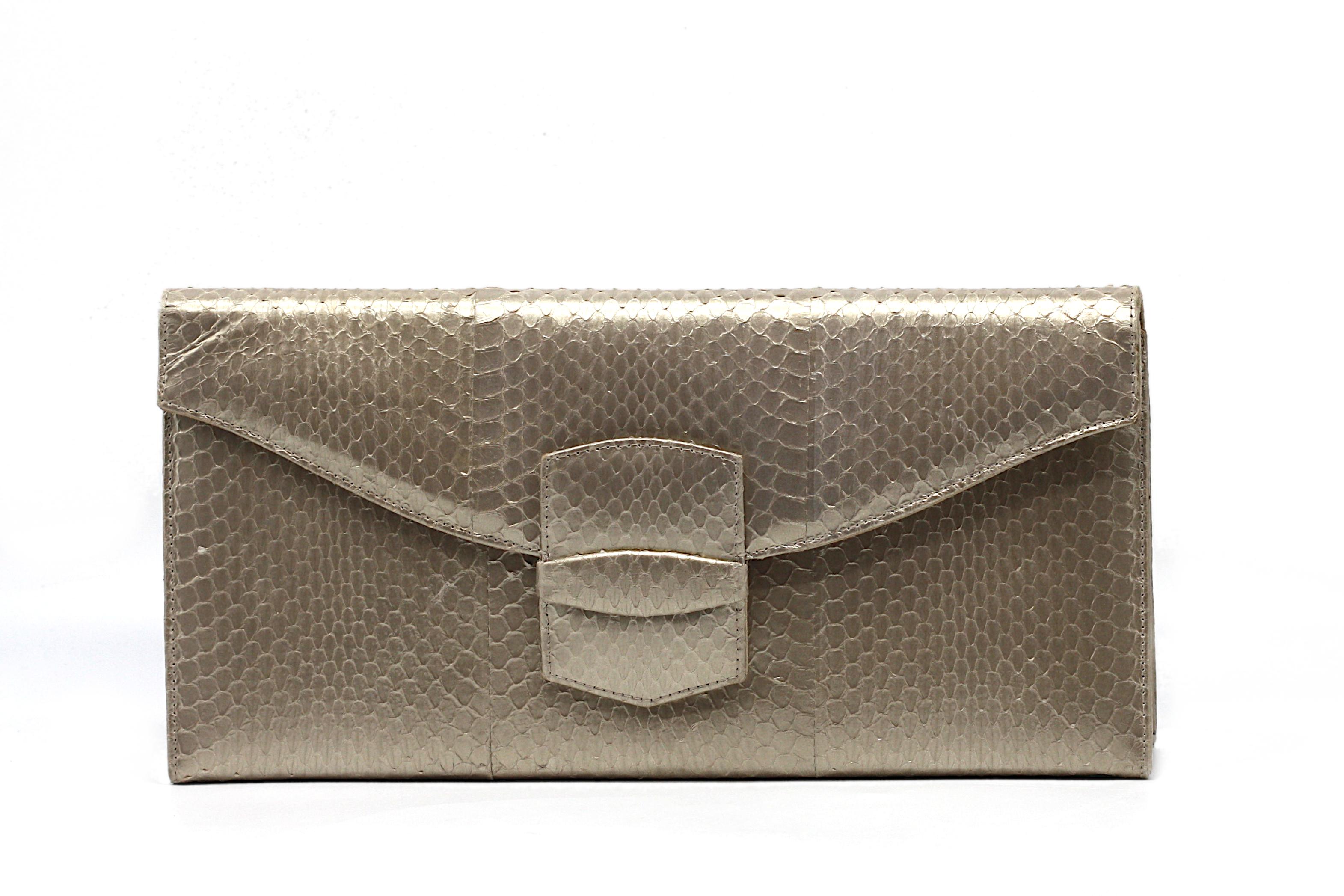 Una straordinaria clutch di Oscar De La Renta, realizzata in pelle di serpente goffrata in un'elegante tonalità oro argentata. L'elegante forma rettangolare presenta una chiusura a scatto magnetica e si apre per rivelare un interno raffinato con una