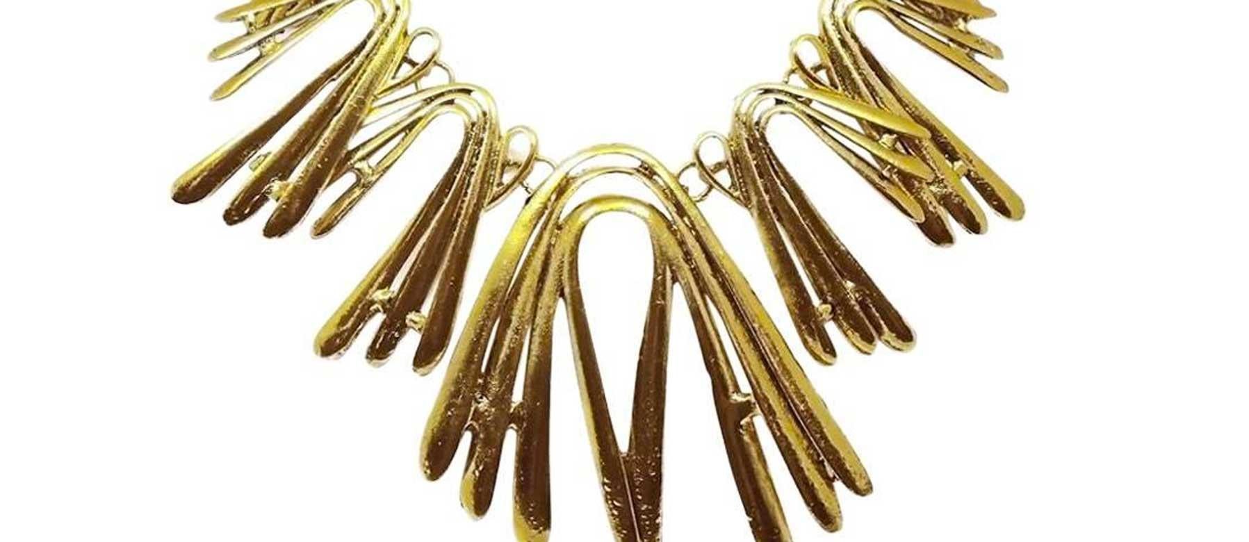 This very much in demand Oscar De La Renta necklace is bent and shaped to look like gentle spikes. It is made in a gold tone setting and has a lobster clasp and measures 19” x 1/4”. The drop from top to bottom measures 4” x 3”. It is signed “Oscar