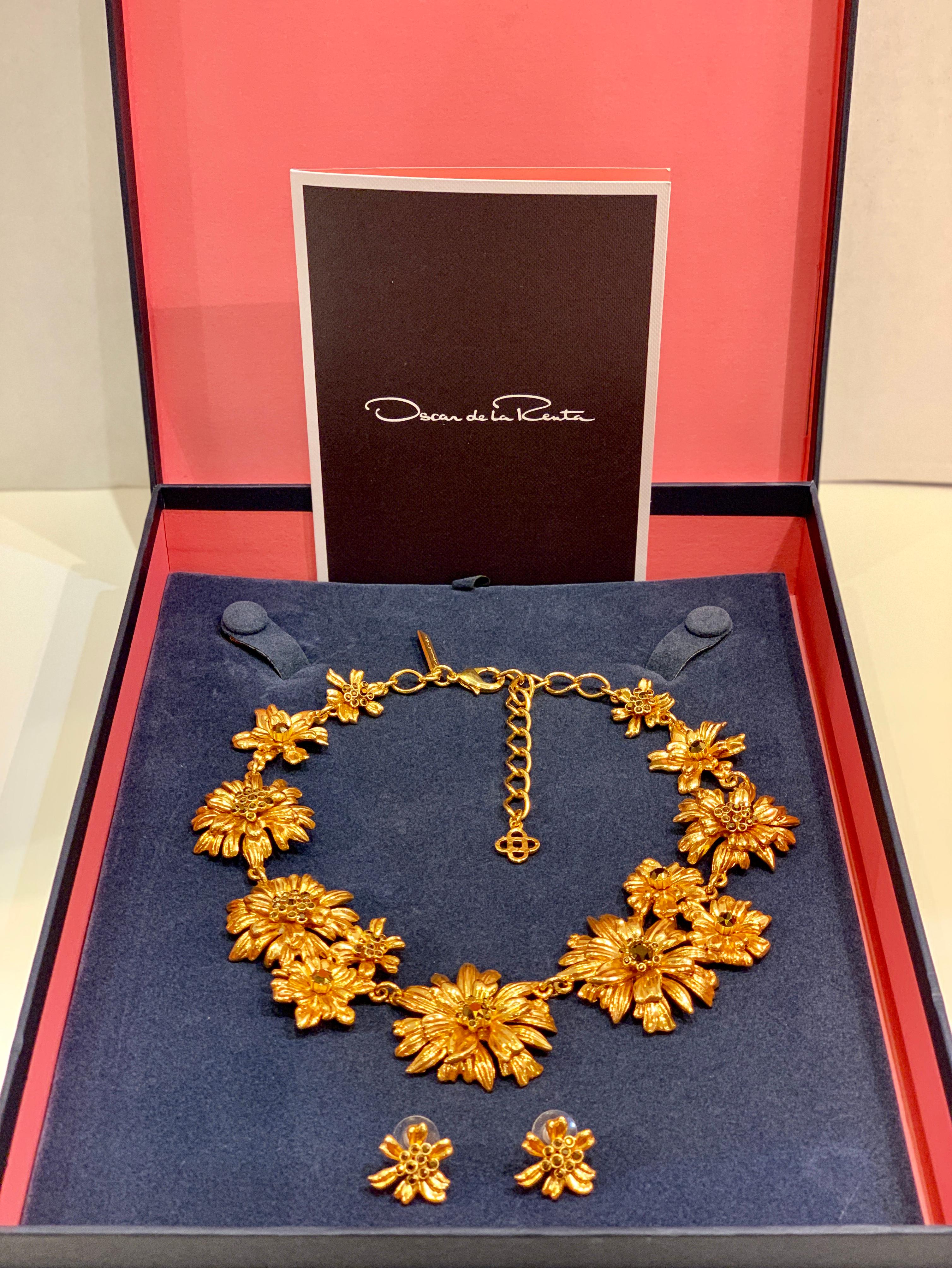 Created by the elite fashion house of Oscar de la Renta, this very substantial statement necklace features a daisy-chain of gleaming blossoms alight with sparkling Swarovski topaz crystals and is accented by matching classic flower button earrings.