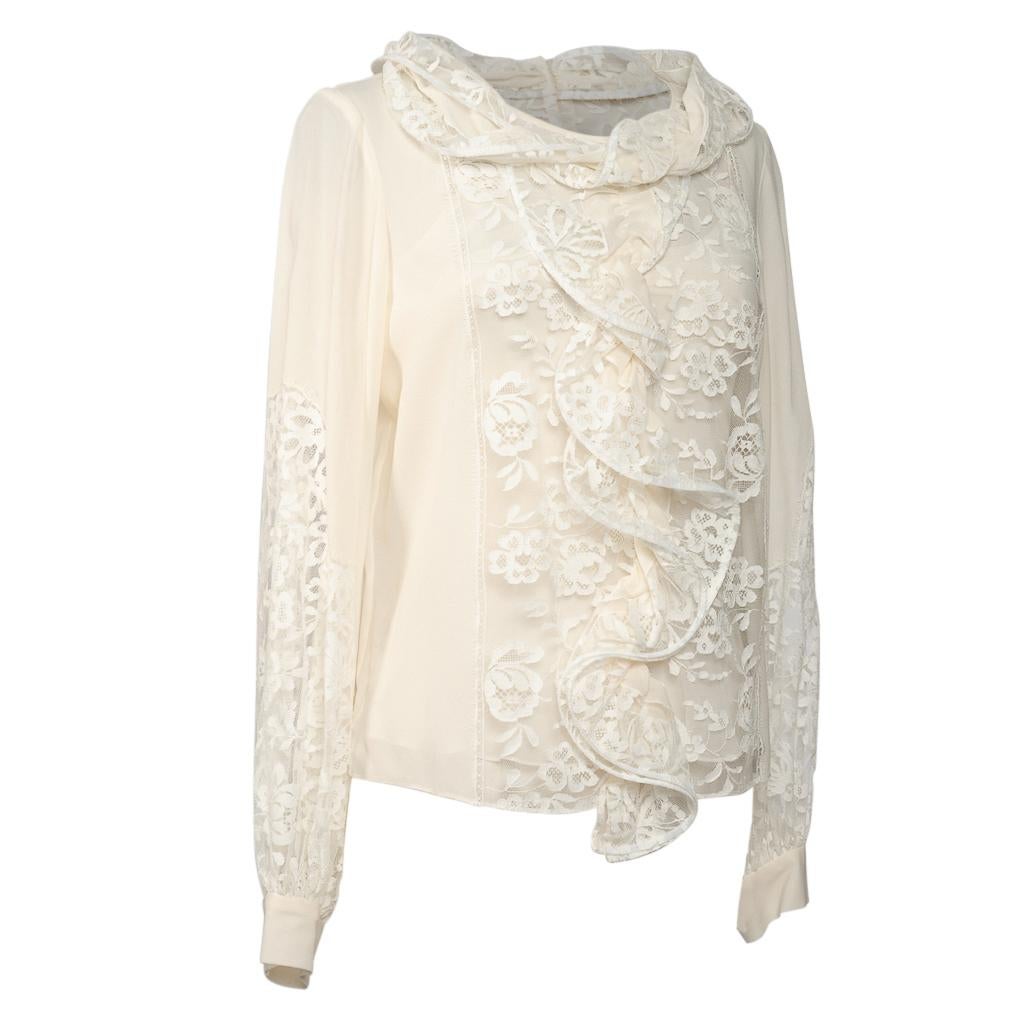 Guaranteed authentic Oscar de la Renta cream silk blouse with rich lace insets.  
Boat neck effect with 'wrapped' drape.
Lush insets of floral lace in front rear and sleeves.
Rear has small buttons for closure.
2 Buttons on each cuff.
Comes with