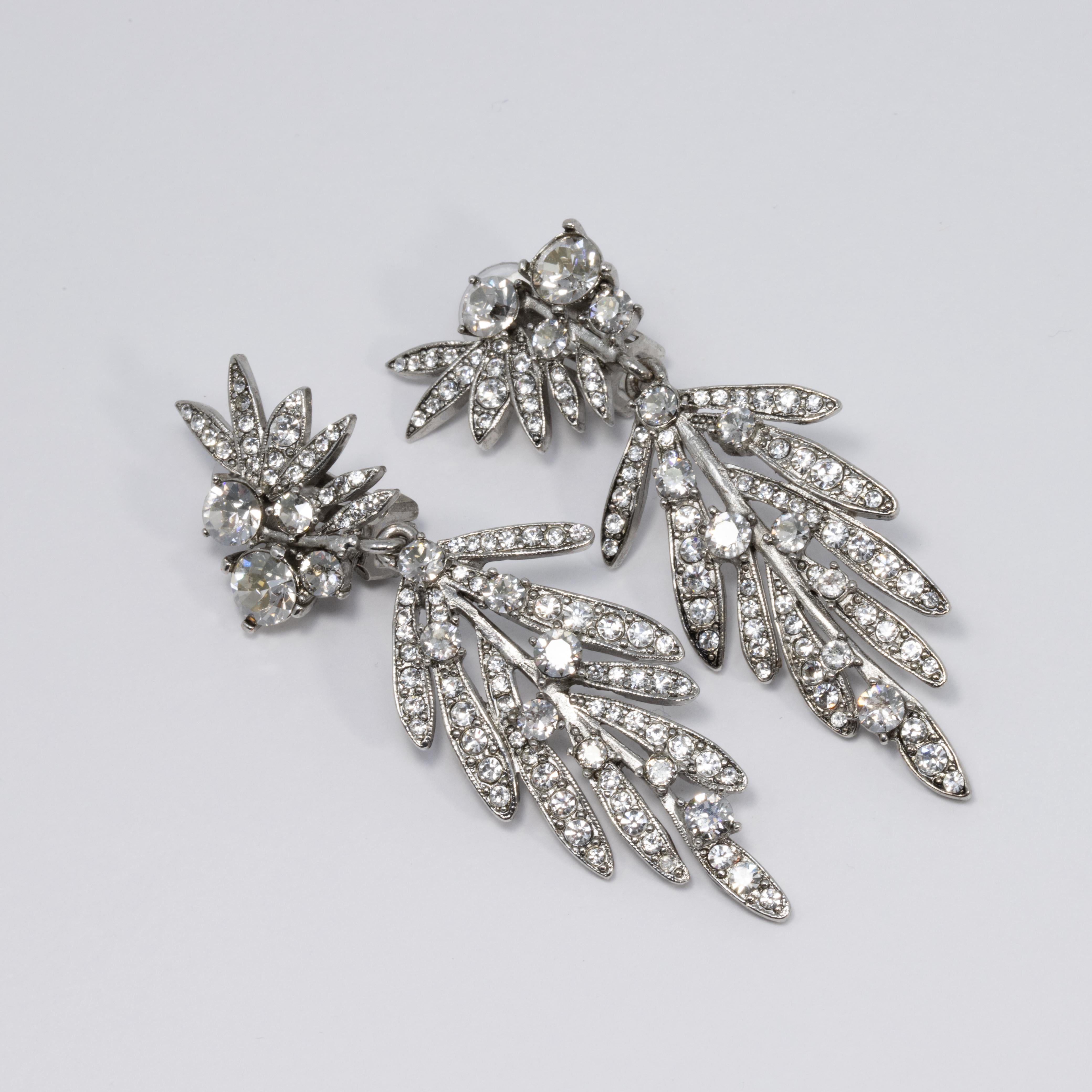 An exquisite pair of earrings by Oscar de la Renta! Each earring features dangling silvertone tropical leaves accented with clear Swarovski crystals. 

Hallmarks: Oscar de la Renta, Made in USA