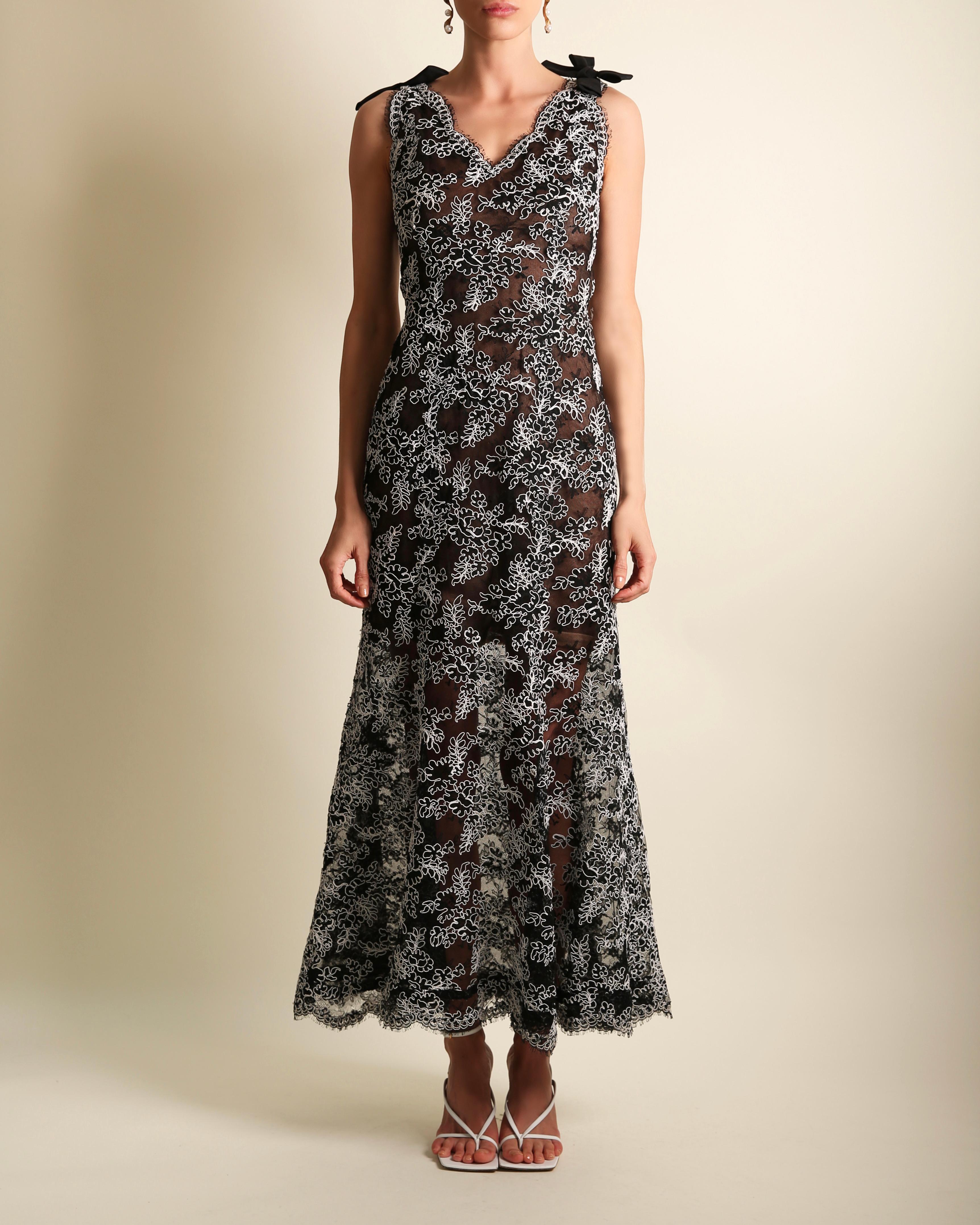 Oscar de la Renta vintage gown
A line cut which consists of a fitted upper and flared skirt 
Black netting with black lace overlay detail with white embroidered floral style detail
Two large black bows to both of the shoulders
Concealed side zip,