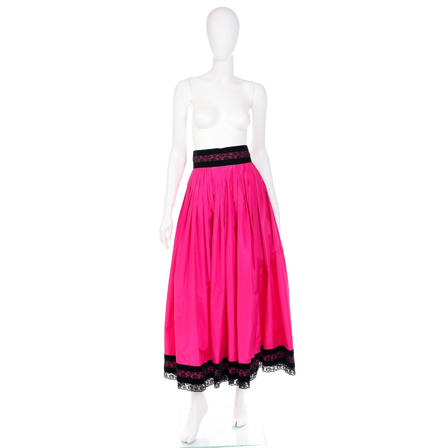This is a bright hot pink silk taffeta Oscar De La Renta maxi skirt with lovely black velvet and black lace trim on the waist and the hem. 
There is a large decorative bow on the back waist with the same black velvet and black lace. The hot pink