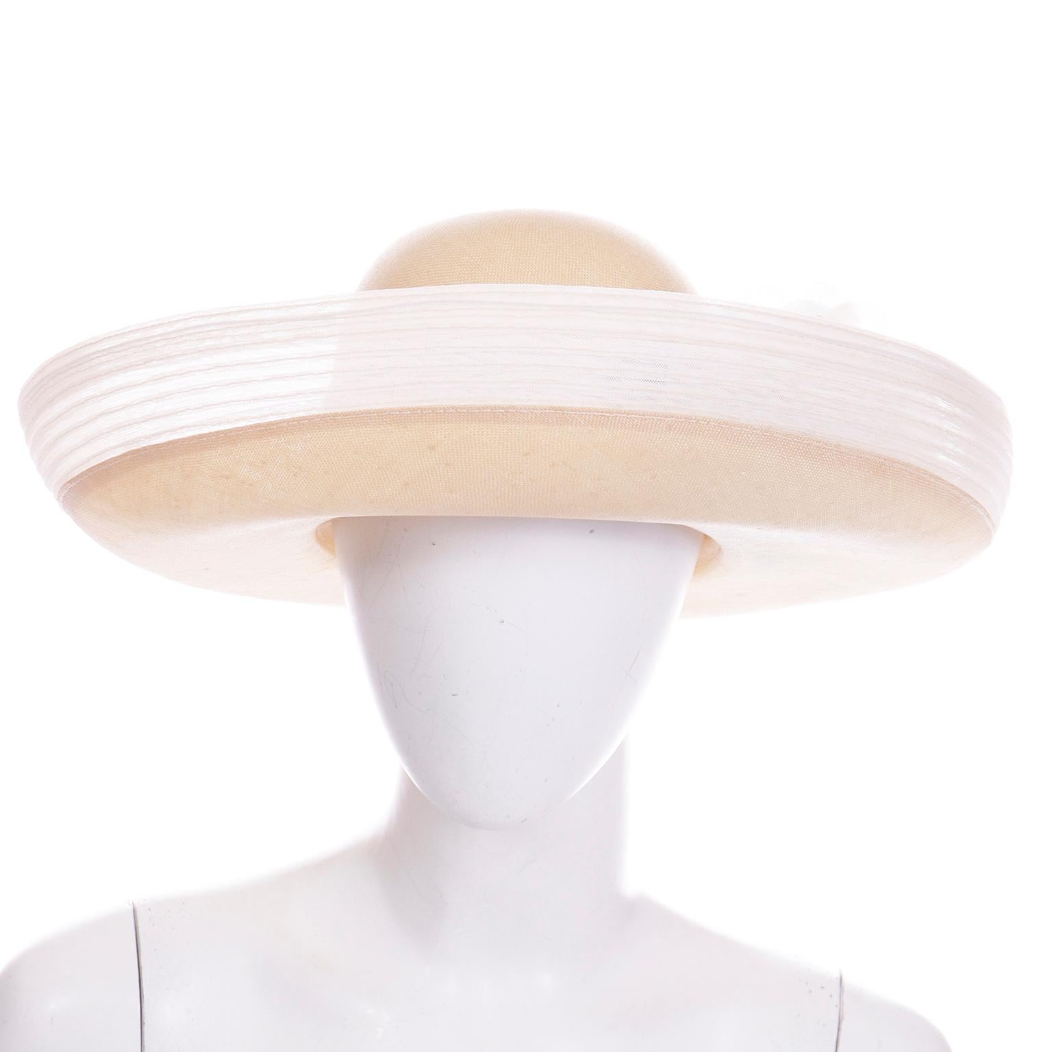 This is a beautiful Oscar de la Renta natural fine straw hat with white mesh that has a really unique top stitch pleating. There is also a white rose applique attached around the base of the hat. It has a beautiful upturn brim with a slightly longer