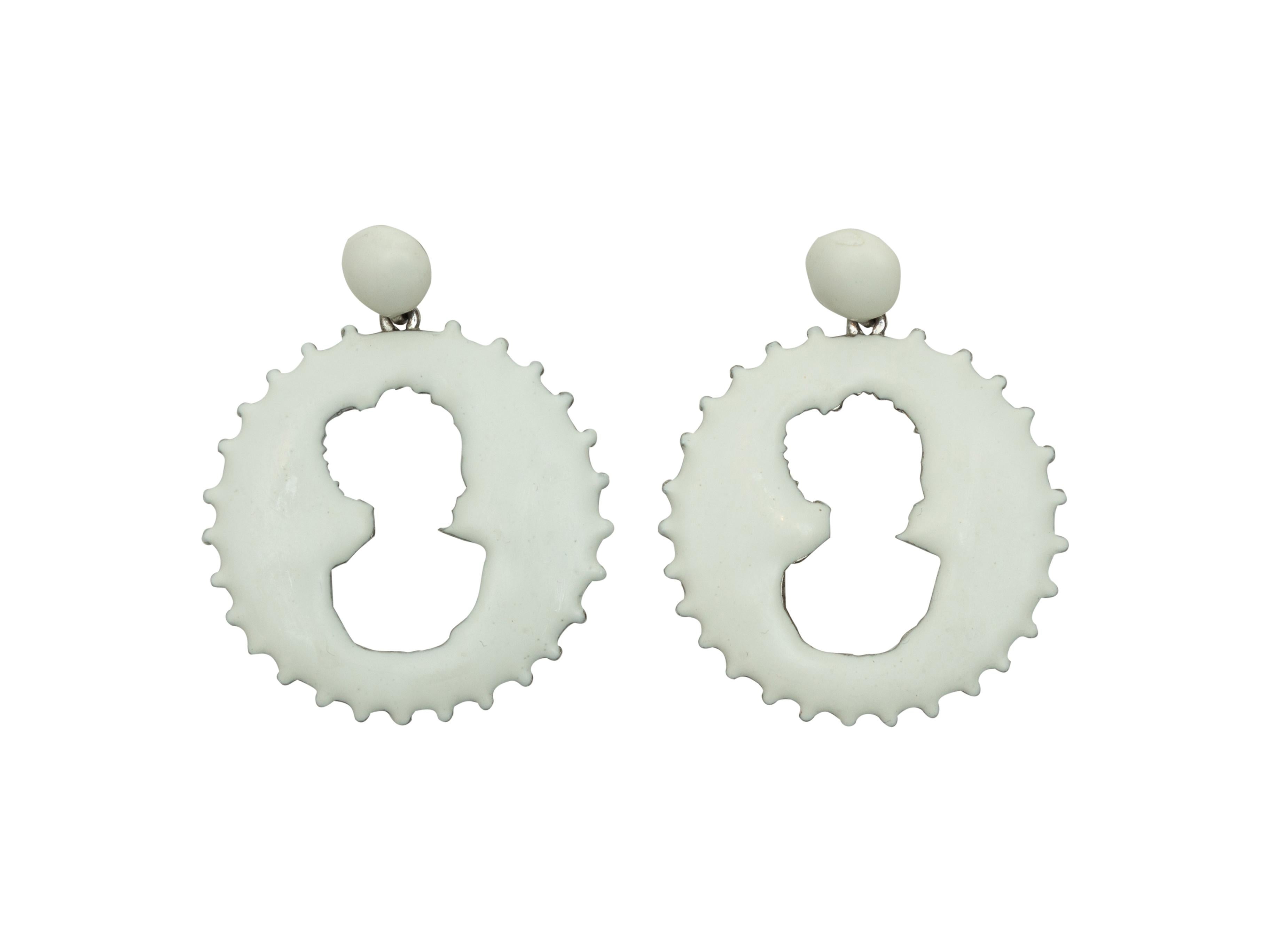 Product details: White disc dangle pierced earrings by Oscar de la Renta. Cameo silhouette cutouts at centers. 2