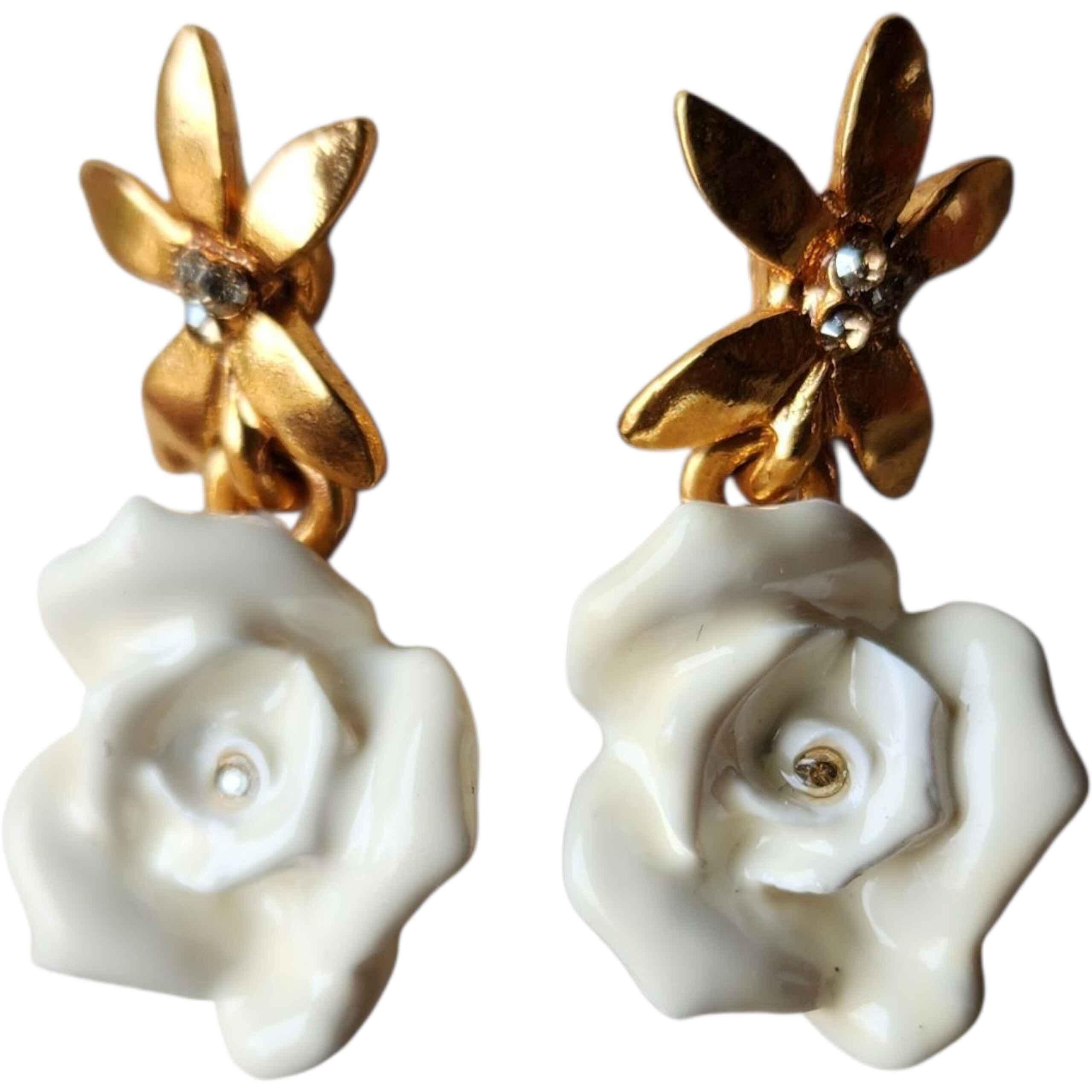 Un paio di orecchini firmati Oscar De La Renta splendidamente romantici, con rose scolpite in resina bianca sospese a perni floreali in tonalità oro scintillanti, accentati da piccoli centri di cristallo. Il design cattura l'iconica miscela di