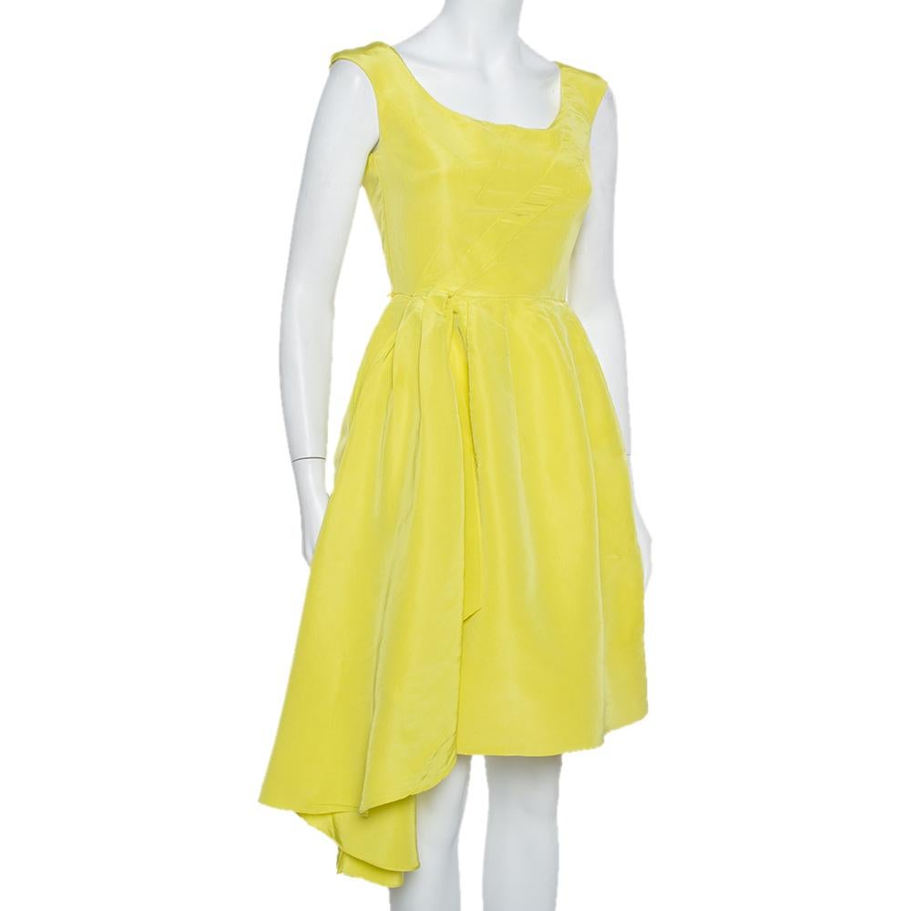 This midi dress comes from the iconic label of Oscar de la Renta. It has a sleeveless silhouette and is made from 100% silk in a vibrant yellow shade. It has a round neckline, front asymmetrical drape details, and a concealed zip closure at the
