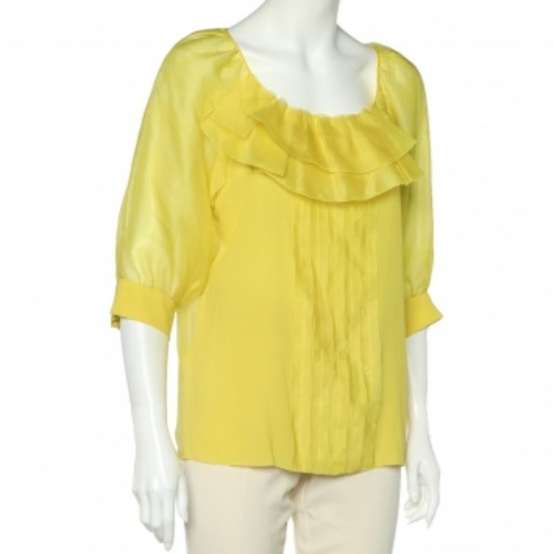 This lovely, bright yellow top from Oscar De La Renta is tailored using smooth silk and organza. The sheer top has elegant ruffle details and will look great with cream or beige pants and high heels.