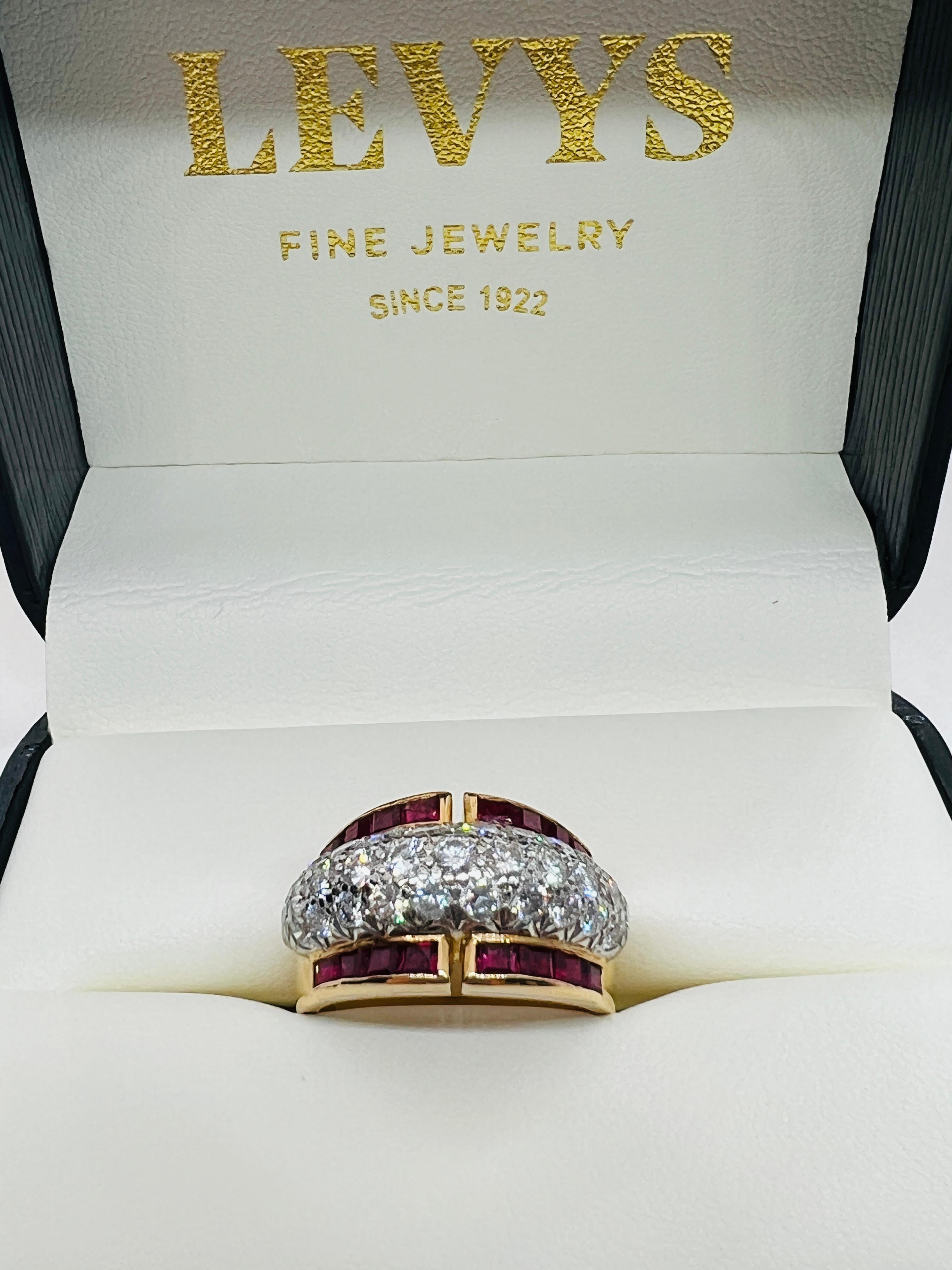 Designer Oscar Heyman Brothers Retro Ring. The ring is made in 18K Yellow gold and has a platinum top that holds three rows of 31 pave set diamonds. The diamonds are flanked by a single row each of calibre cut rubies. The ring is 12.3mm wide at its