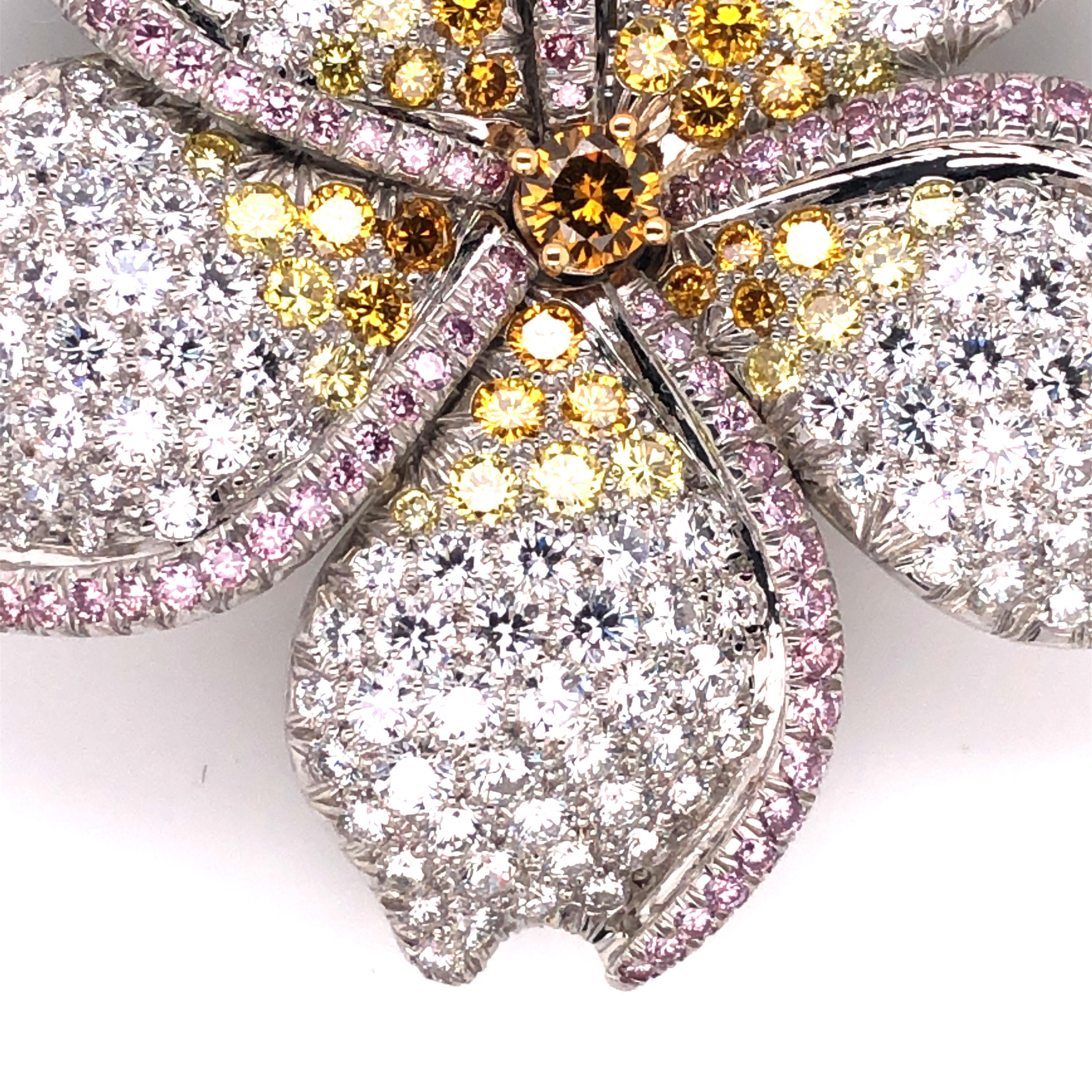 Oscar Heyman platinum and 18k yellow gold flower brooch contains 204 round diamonds (7.05tcw, F-G/VS+), 40 round fancy yellow diamonds (1.75tcw), 95 fancy pink diamonds (1.21tcw) and a fancy yellow diamond center weighing 0.27cts. It is stamped with
