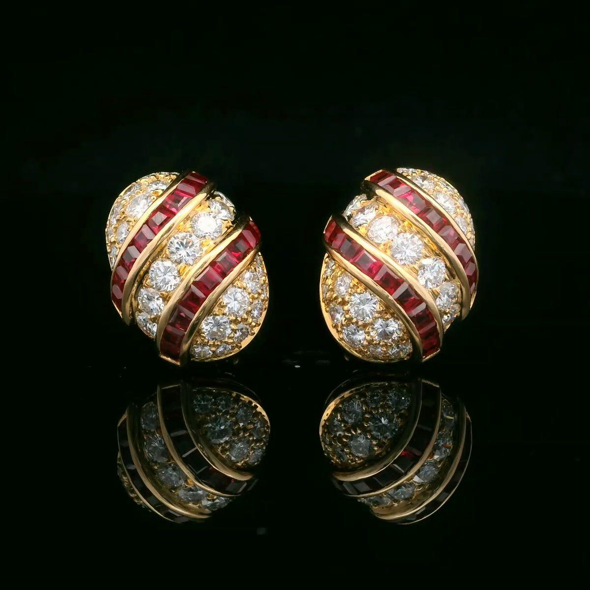 Questo paio di orecchini in oro giallo 18kt di Oscar Heyman contiene 2,82 carati di rubini calibrati in due eleganti volute intorno a un ovale di 50 diamanti rotondi del peso di 2,90 carati (F-G/VS+). I rubini sono stati realizzati a mano dal