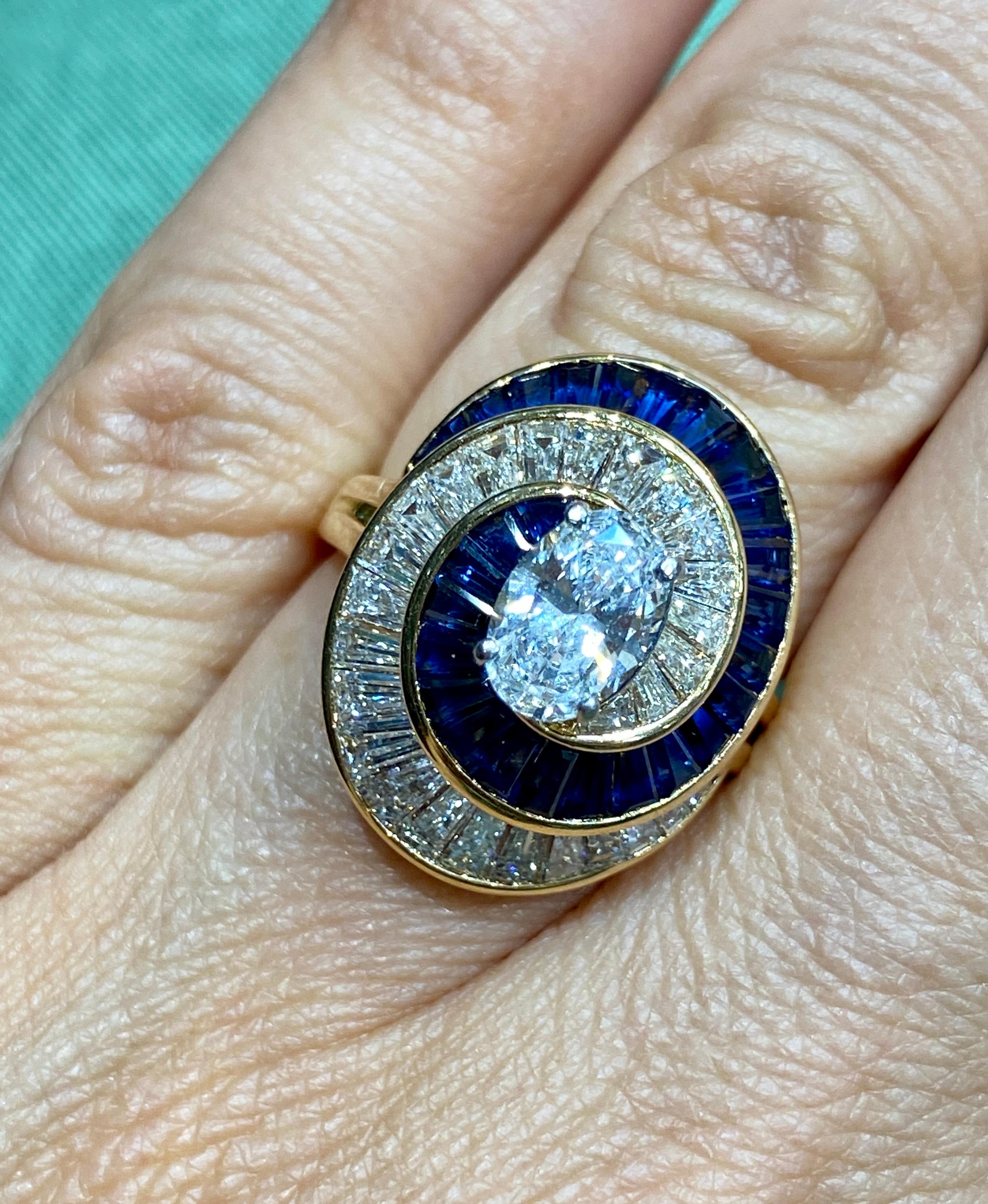 Dieser auffällige Oscar Heyman Ballerina-Ring aus den 1960er Jahren ist um einen ovalen Diamanten von ca. 0,8 Karat herum angeordnet. Der Mittelstein ist umgeben von ca. 1,5 Karat konisch zulaufenden Baguette-Saphiren und ca. 1,9 Karat konisch