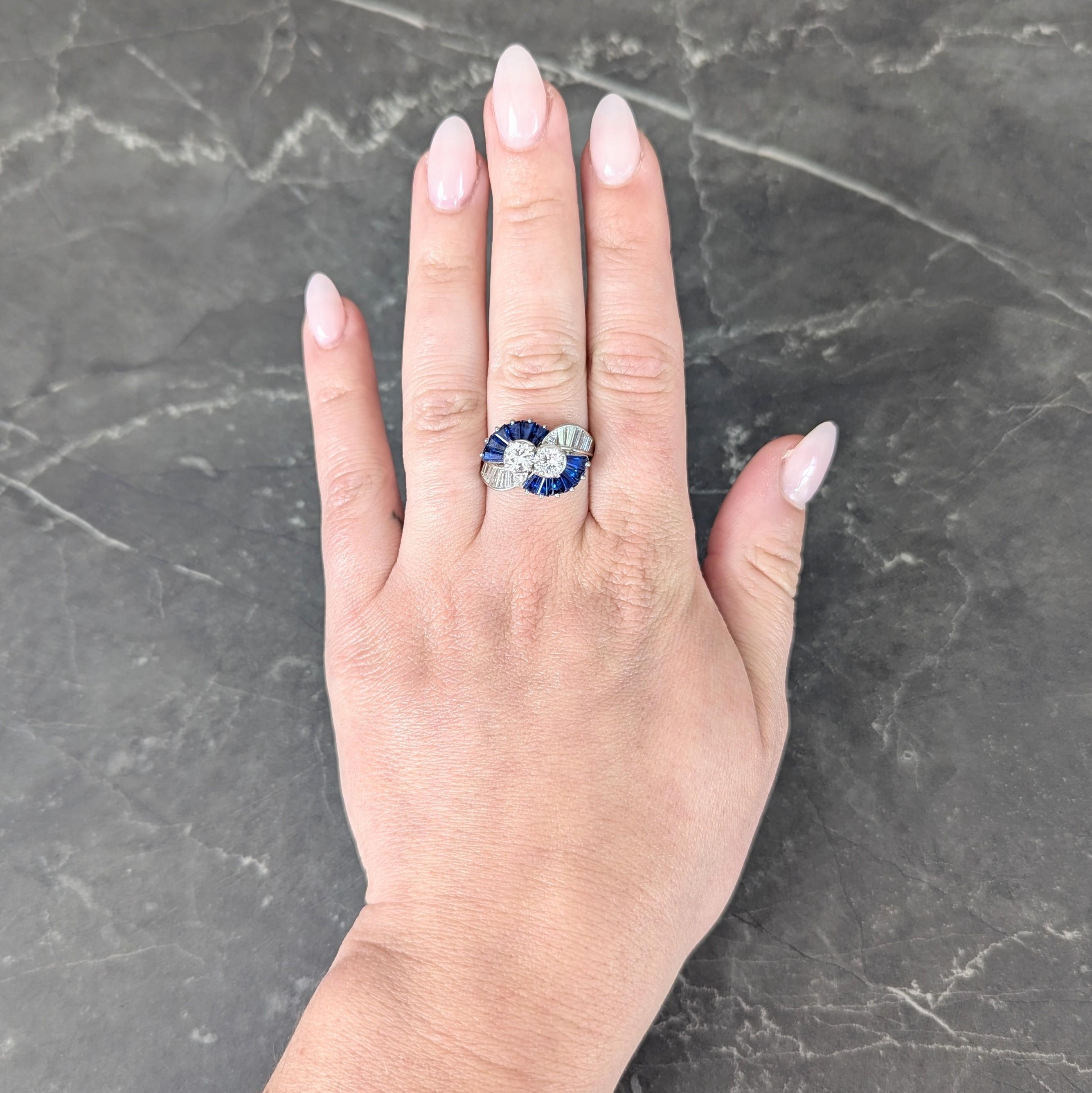 Ring im Bypass-Stil mit zwei Diamanten im Übergangsschliff in der Mitte
Mit einem Gesamtgewicht von etwa 1,04 Karat - beide haben die Farbe G und die Reinheit VS2
Flankiert von fächerförmig angeordneten, spitz zulaufenden Saphiren im