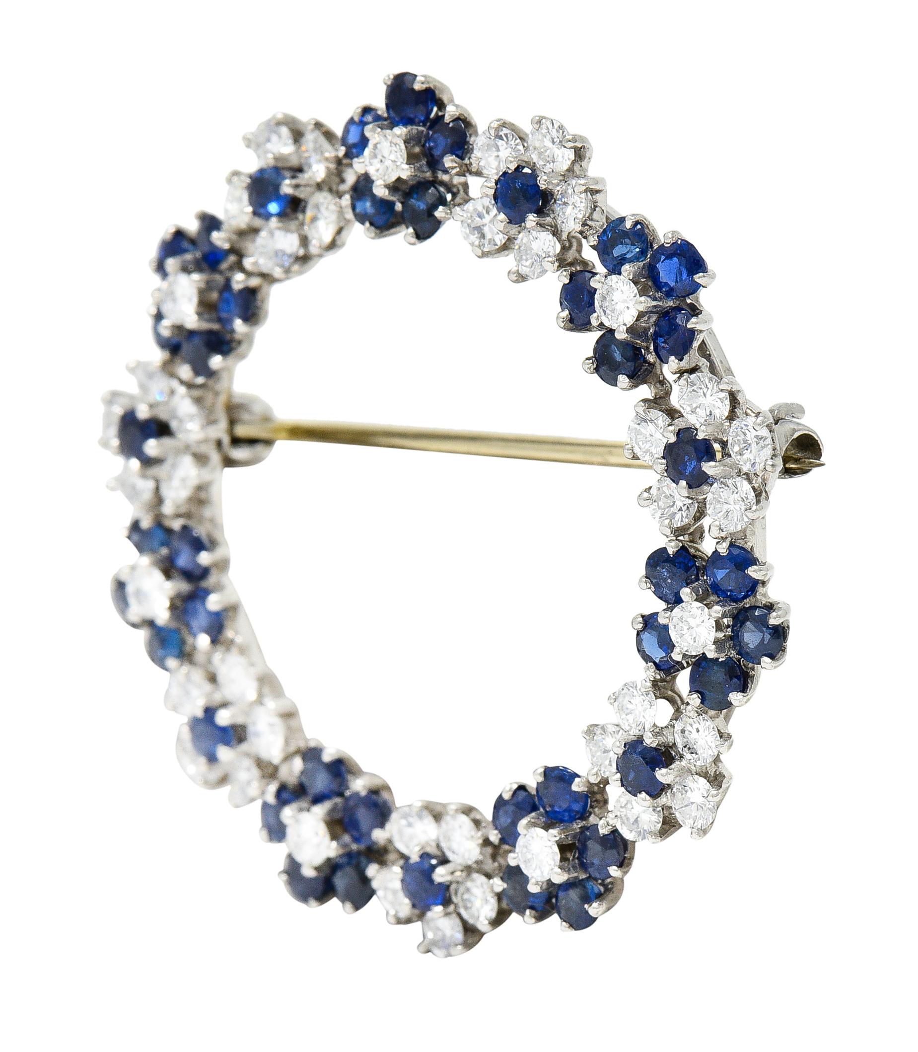 Circular brooch comprised of floral clusters of sapphires and diamonds

Round cut sapphires are well matched in strong royal blue color

Weighing in total approximately 1.80 carats

Round brilliant cut diamonds weigh in total approximately 1.25